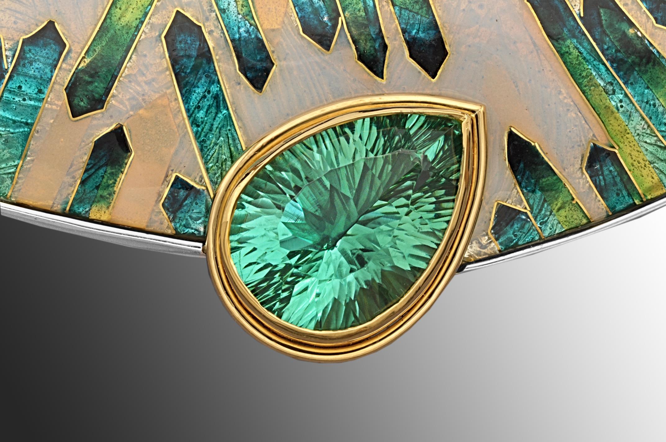 The asymmetric cloisonné enamel brooch is a one of a kind brooch and is named VERDANT. It is inlaid with 24 karat yellow gold. The enamel is bezel set in sterling silver and the 13.6 carat Appetite stone set in 18 karat yellow gold. This statement