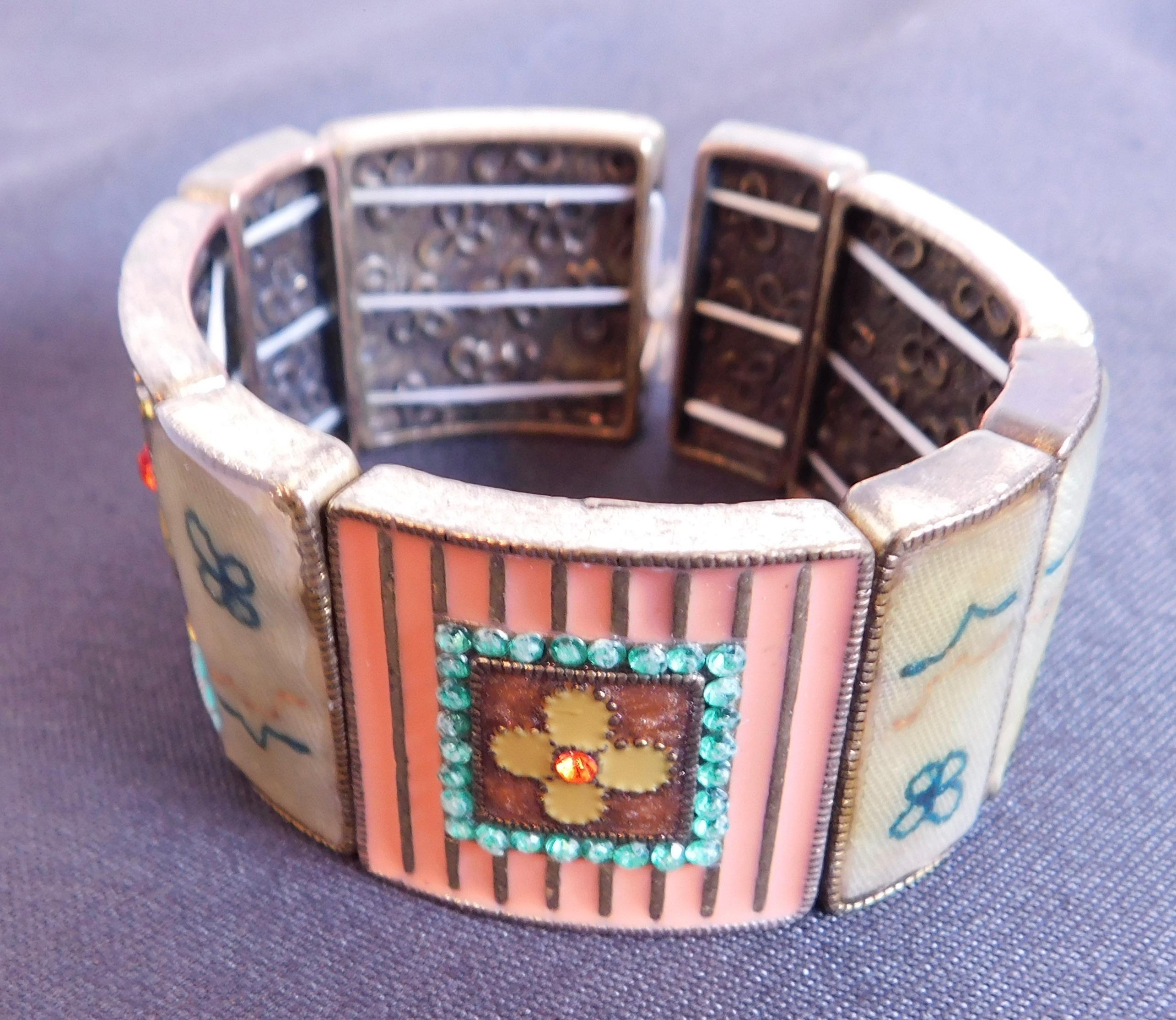 A most unique bracelet of cast metal elements decorated in cloisonné enamel ,inset with coloured rhinestones , and antique fabric fragments set under acrylic .
The pieces are joined together with elastic to allow for a stretch fit.
The actual date