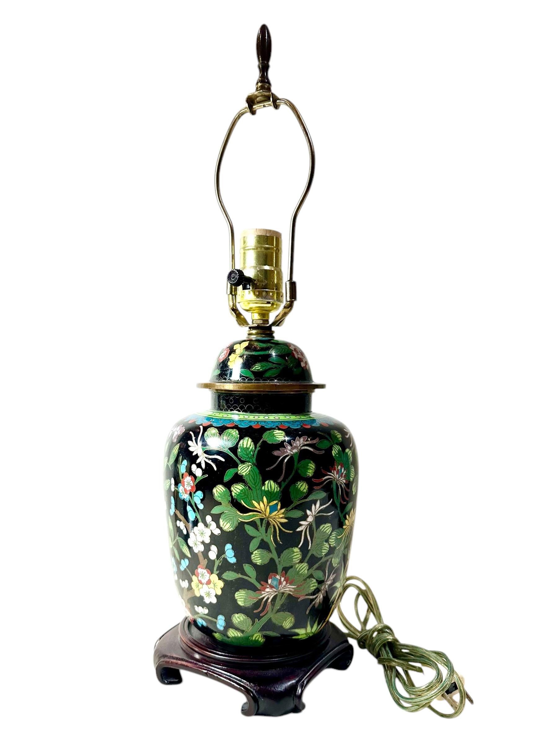 A beautiful 19th century Chinese cloisonné ginger jar lamp on a wooden stand. The lamp has a nice long cord, a finial and a harp.