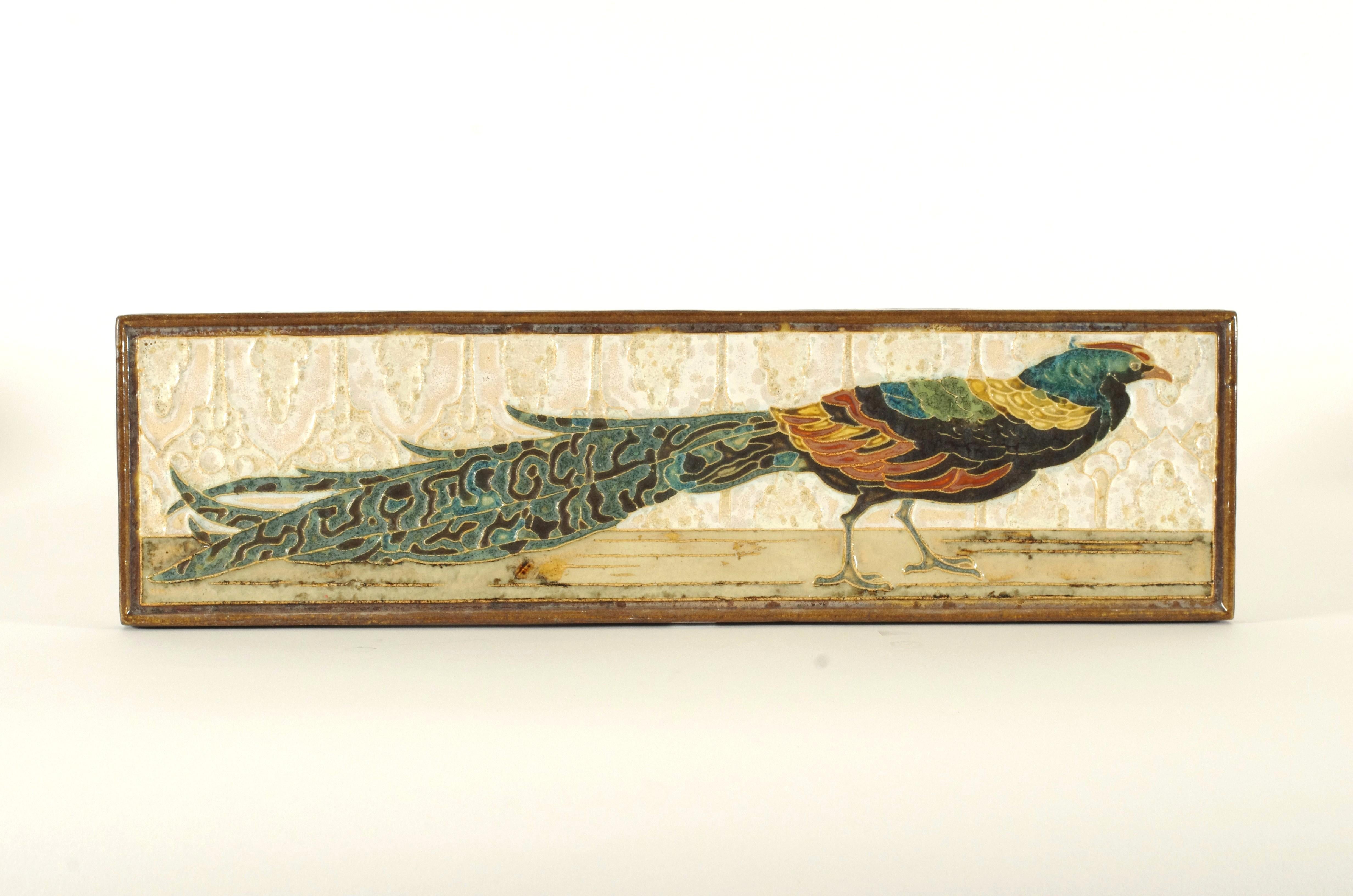 Rectangular cloisonné tile designed by L.E.F. Bodart for De Porceleyne Fles in Delft, decorated with a long-tailed pheasant in rich polychrome glazes. The bird is rendered in green, blue, ochre, red (rust tones) and black, set against a soft