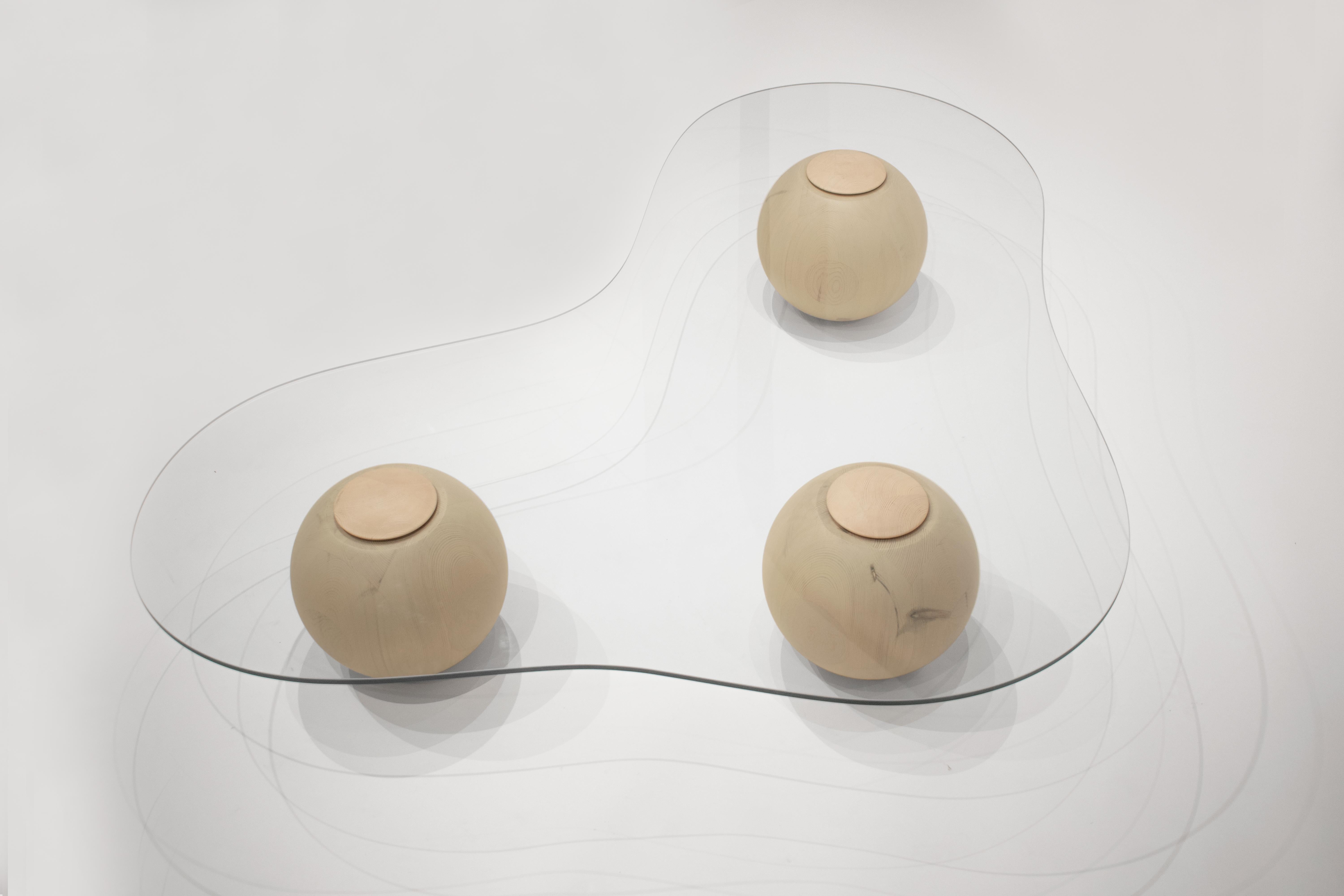 Tempered glass with three solid wooden lacquered spheres.

Captured on the moment of transition, this low glass table takes the form of a smooth cloud. Fluid yet meticulously defined in its shape, the CLOUD is solidified on the moment of rest.