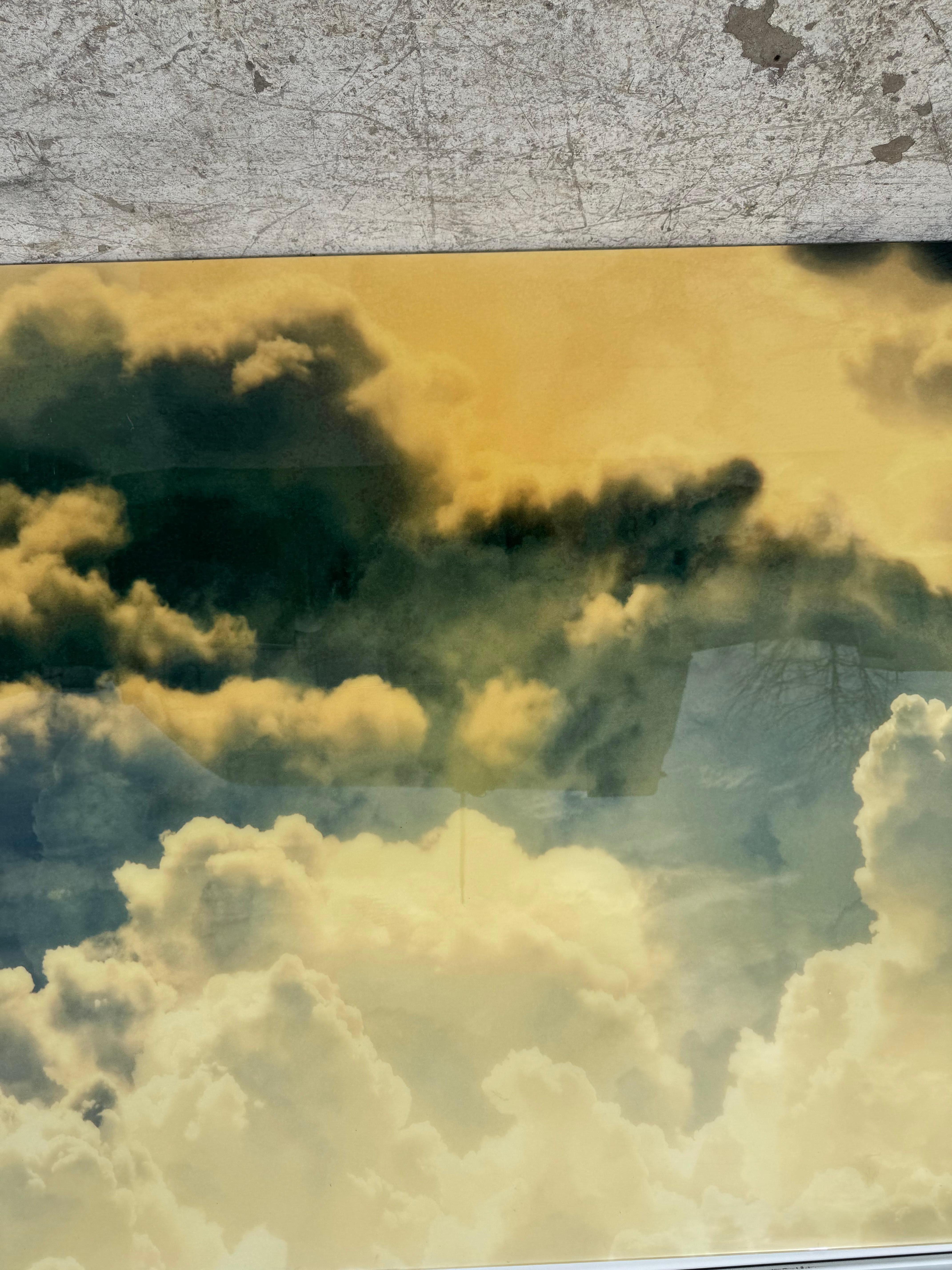 Este cuadro presenta un cielo dramático lleno de nubes arremolinadas en tonos de verde intenso y amarillo dorado. El contraste de tonos oscuros y claros crea una sensación de mal humor y atmósfera, evocando una sensación de misterio y movimiento.