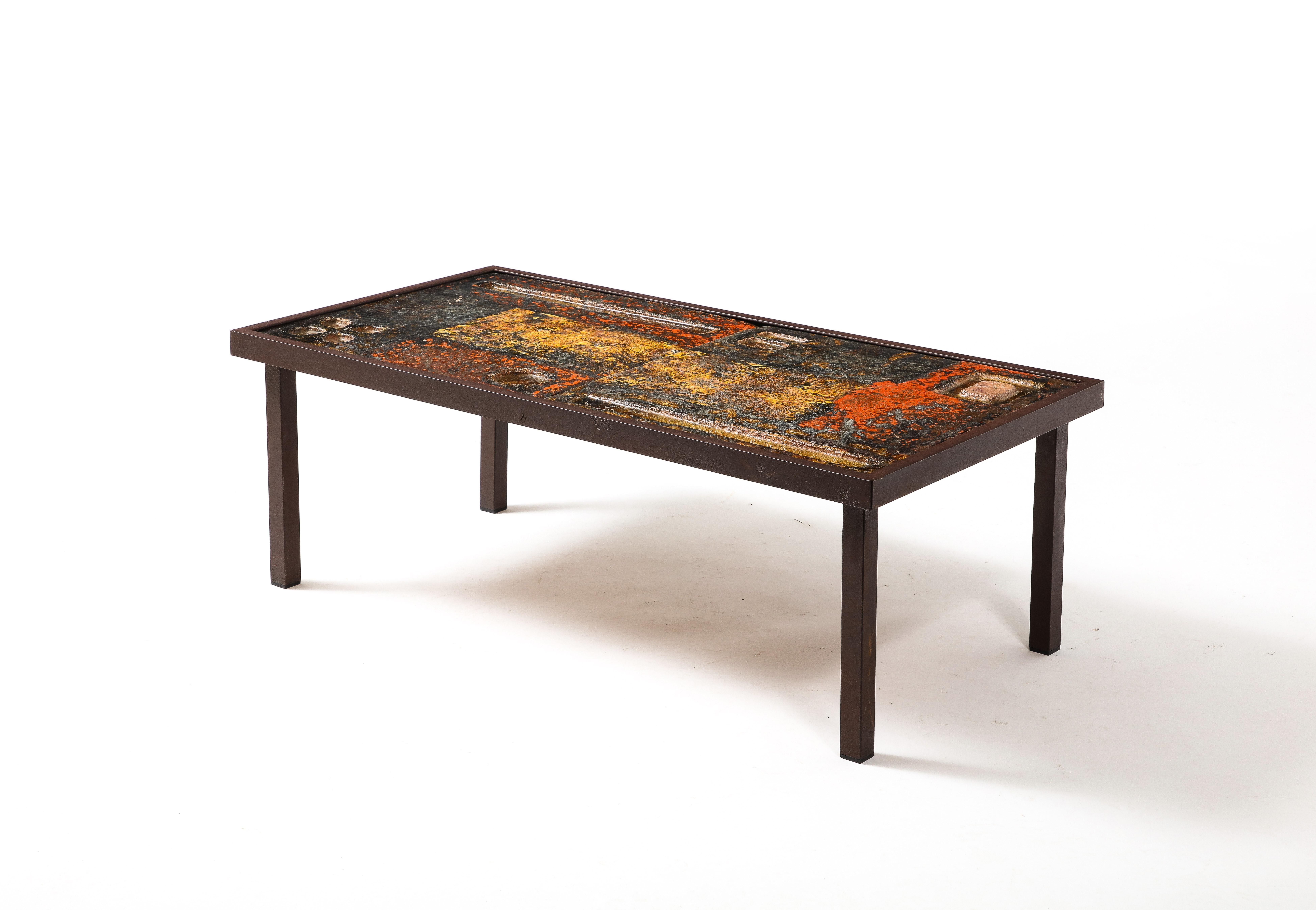 Enameled lava table with fused glass inlays on a patinated steel base.
