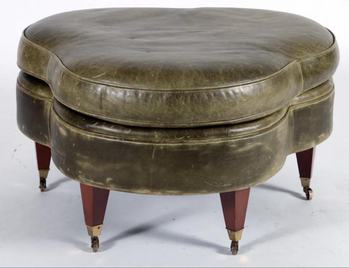 Pouf Clover Leaf Form A en cuir vert 
Pieds coniques en bois avec roulettes en laiton.
Il s'agit d'un ottoman en forme de trèfle, recouvert d'un riche cuir vert olive. Le meuble est doté d'un plateau paddé et d'une double rangée de garnitures en