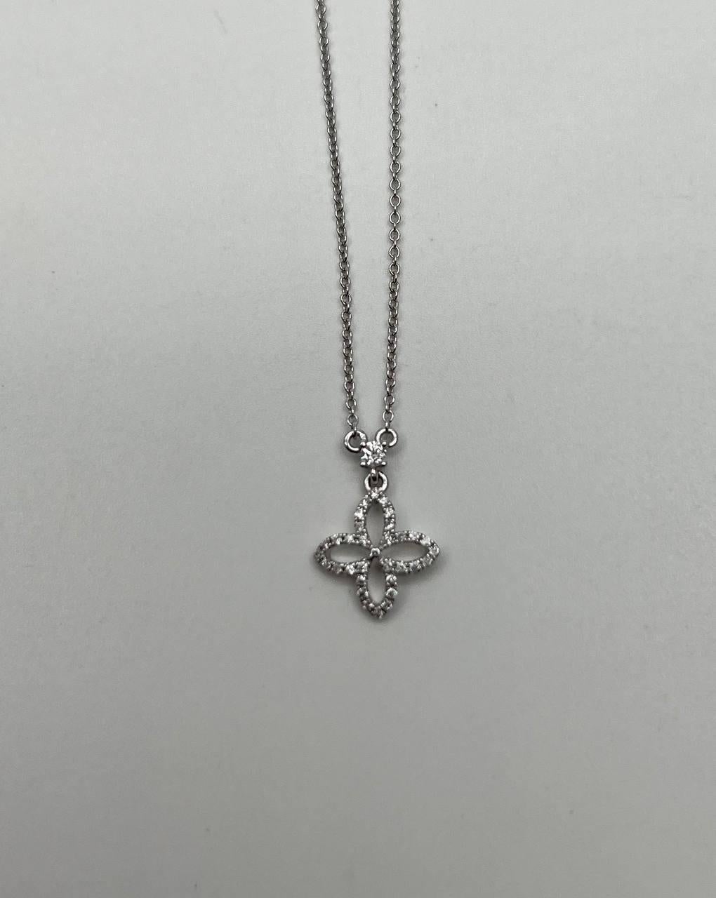 Cet élégant collier à pendentifs présente un délicat motif ajouré. Le pendentif est orné de diamants blancs étincelants, totalisant 0,17 carats, sertis dans de l'or blanc 14k lustré. Le motif complexe forme un gracieux motif floral, ajoutant une