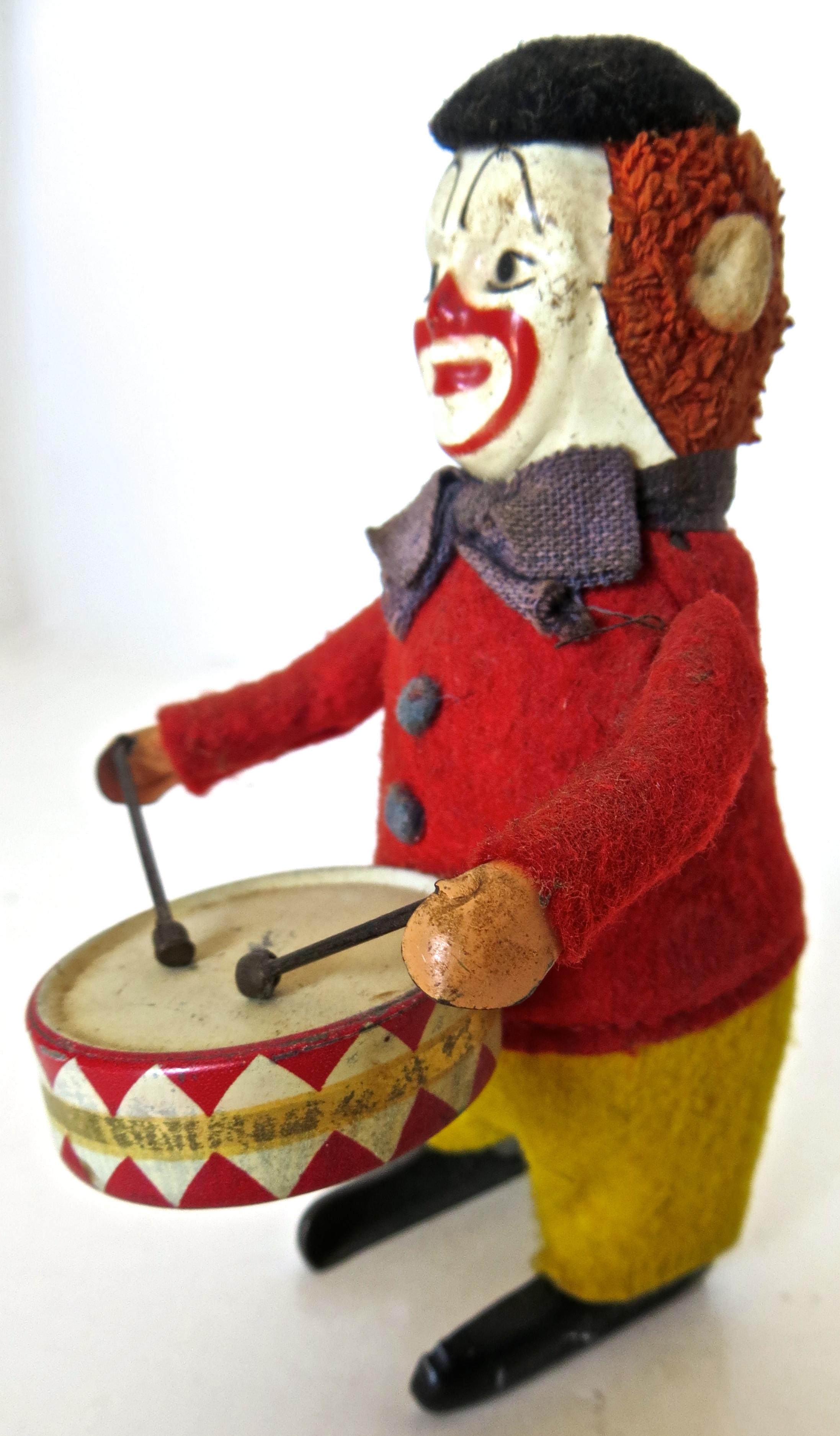 When wound up this charming German Schuco toy clown dances around, while raising his arms up and down playing the drum. In excellent all original condition, he has a tin face and drum, and in dressed in a red felt vest with yellow trousers, and a