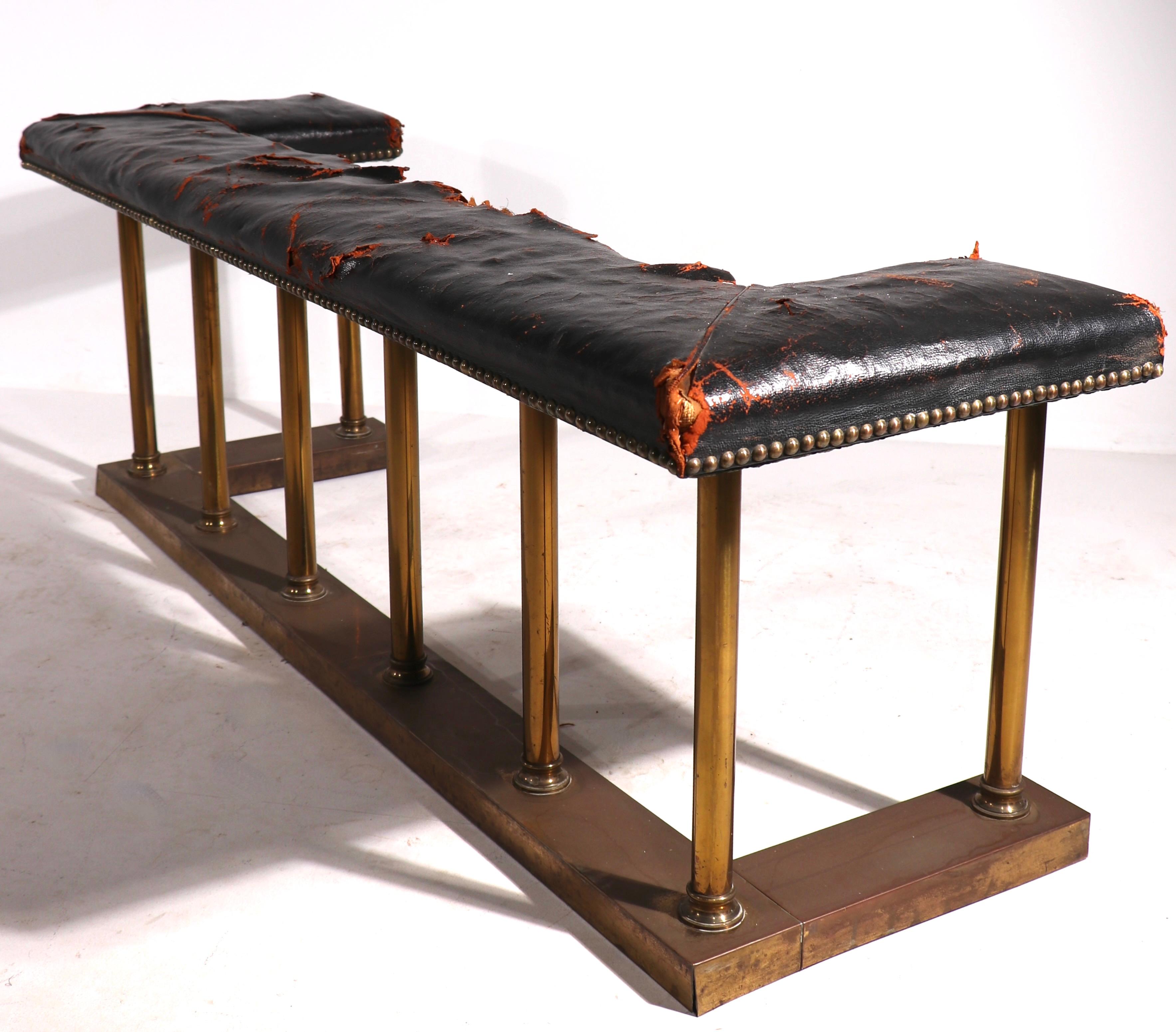 Classical brass and leather club, or bench fender, having a columnar brass base with studded leather seat. The upholstered seat shows significant wear, please see images.
 Tailored design works well with both modern and traditional interior spaces.