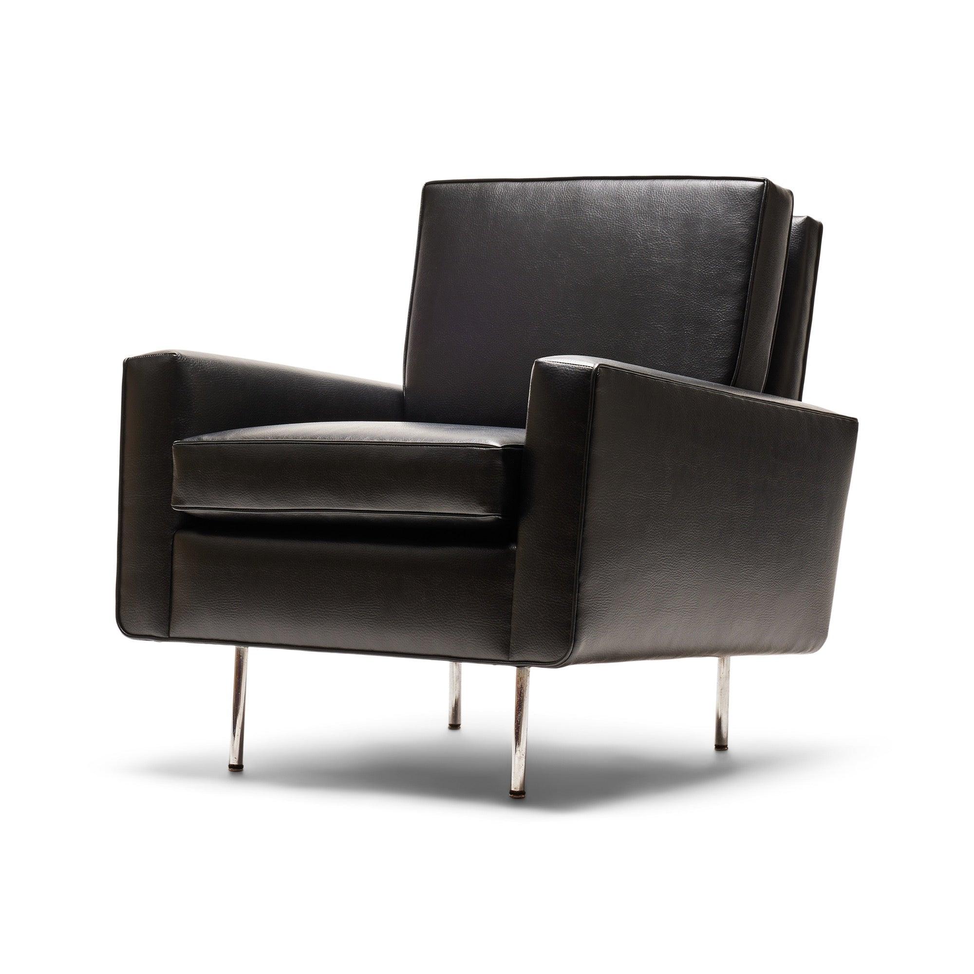 Sillón de diseño temprano de Florence Knoll, totalmente tapizado, con respaldo y cojines de asiento sueltos. Los brazos tienen una sutil inclinación hacia atrás, y todo el armazón se eleva mediante cuatro patas de varilla de acero con acabado