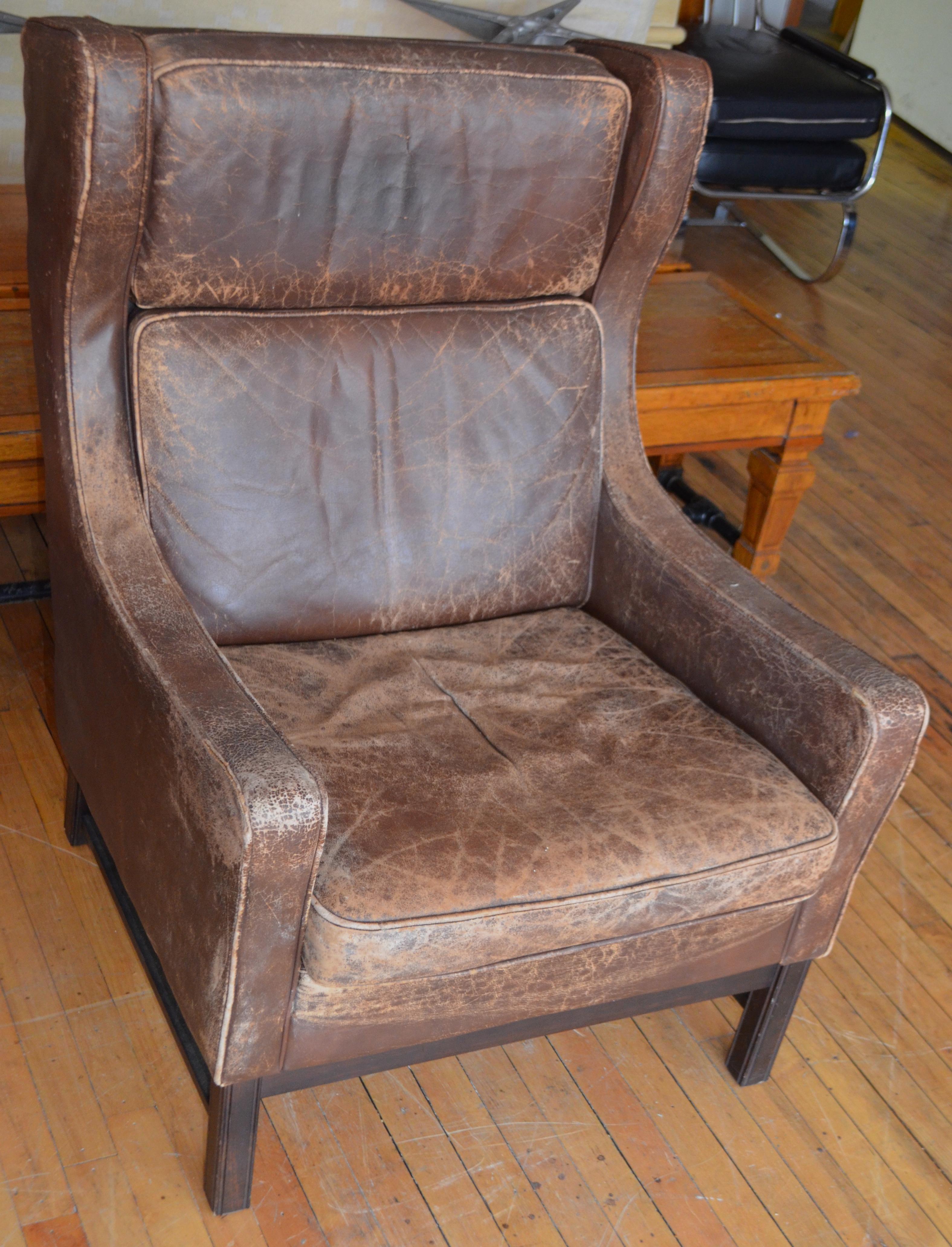 Leather club wingback chair from Edwardian England, early 20th century. The worn leather of this chair has such a hand as to embody all those who sat upon it. A furnishing from a Thomas Hardy novel where the vicar sat every Saturday evening with a