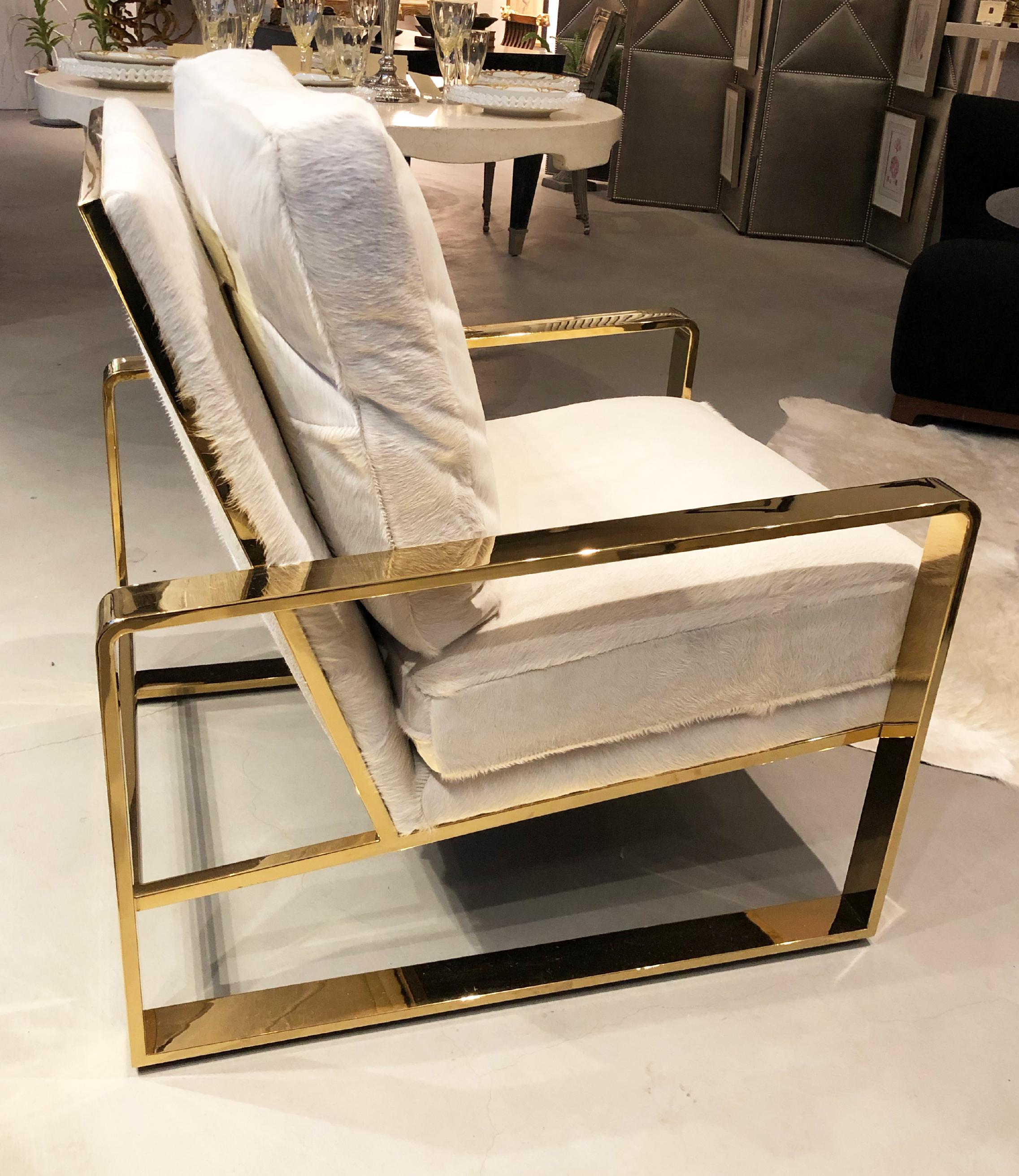 Contemporary club chair with an off-white cowhide upholstery and polished brass frame.