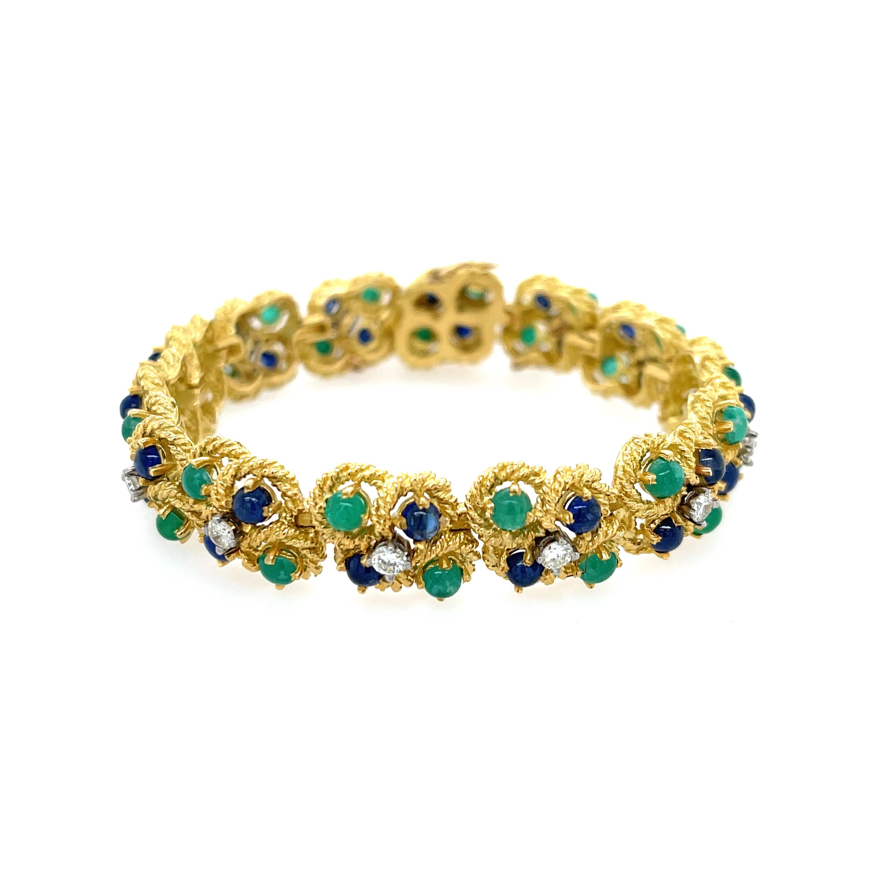 Cluster Emerald, Sapphire, and Diamond Bracelet in 18K Yellow Gold. The bracelet features 28 cabochon emeralds, 28 cabochon sapphires, and 14 round diamonds (1ctw, H color, SI1 clarity).
8