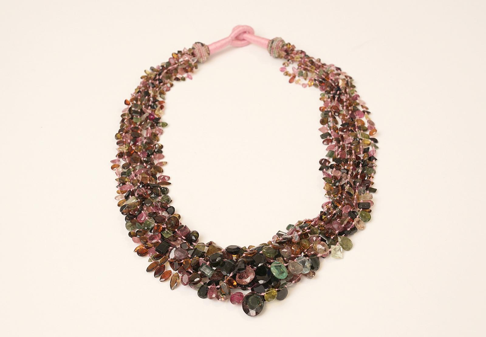 A  multi-strand and slightly graduated cluster necklace of faceted tourmaline beads.  Each bead has a different shape, some are emerald cut, ovals, round heart-shaped, marquise-cut; and all in a variety of shades of tourmaline.  Strung at the top of