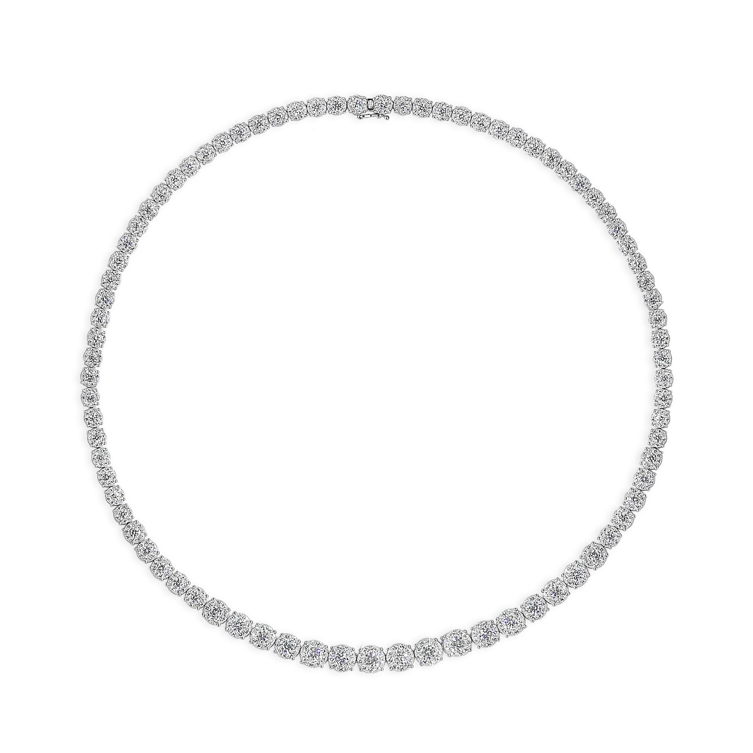 A uniquely-designed graduating tennis necklace showcasing clusters of round brilliant diamonds to make it look like one large diamond! Set in an 18 karat white gold mounting. Diamonds weigh 10.24 carats and are approximately F-G color, VS-SI