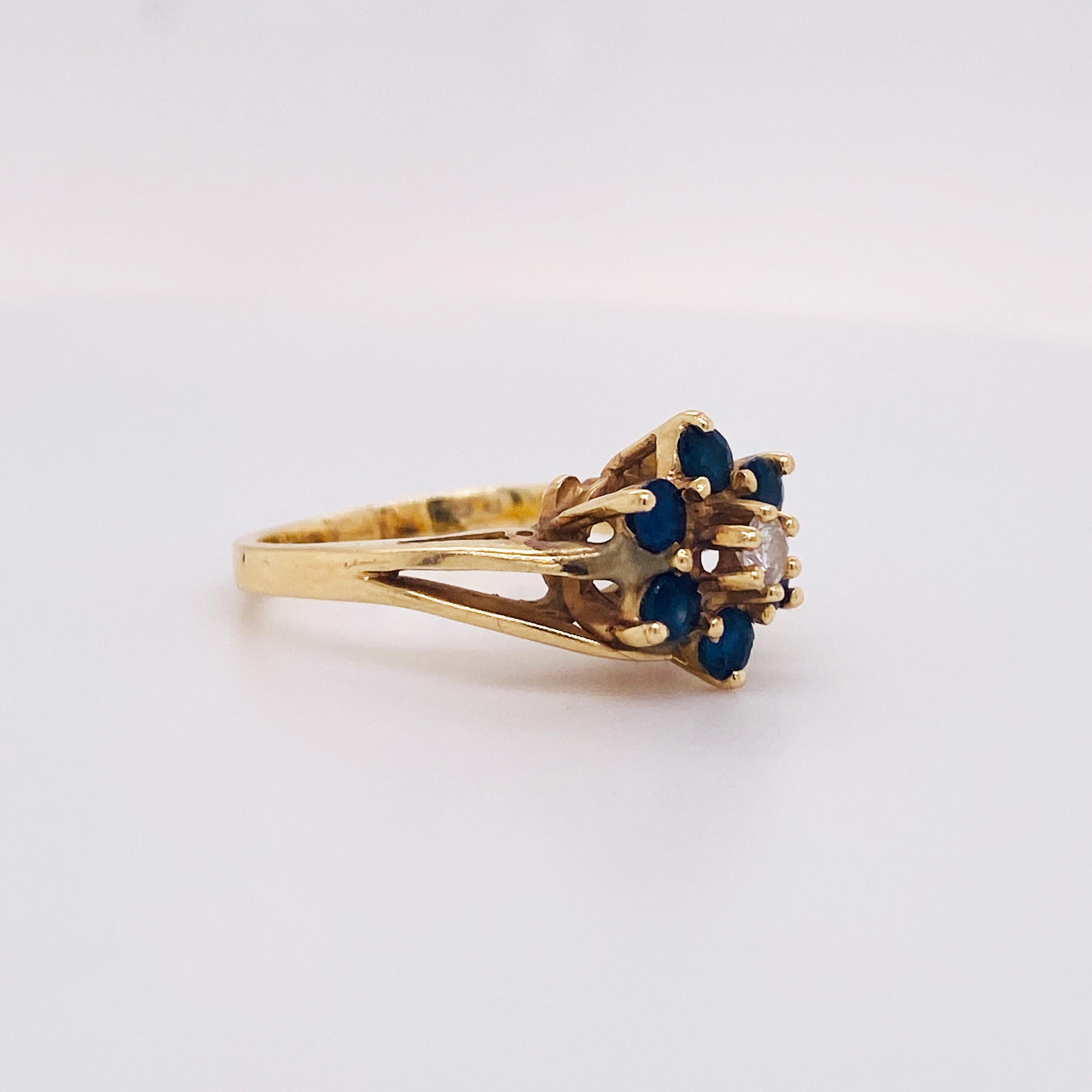 This gorgeous estate floral cluster ring was created in 1990. It has a nice weight and has six lovely blue sapphires that have a total weight of .40 carats and a center diamond that is .06 carats. This ring has a nice thick band and and sides. This