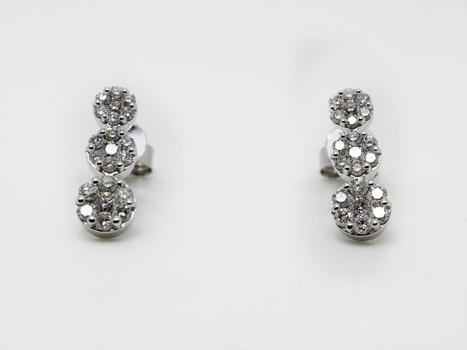 An impressive pair of graduated flower cluster earrings,  featuring a total of just under 1.00 carat diamond (0.99 carat)  of round brilliant cut 7 stones diamond in each cluster colour G / H clarity SI with three clusters per drop. The centre stone