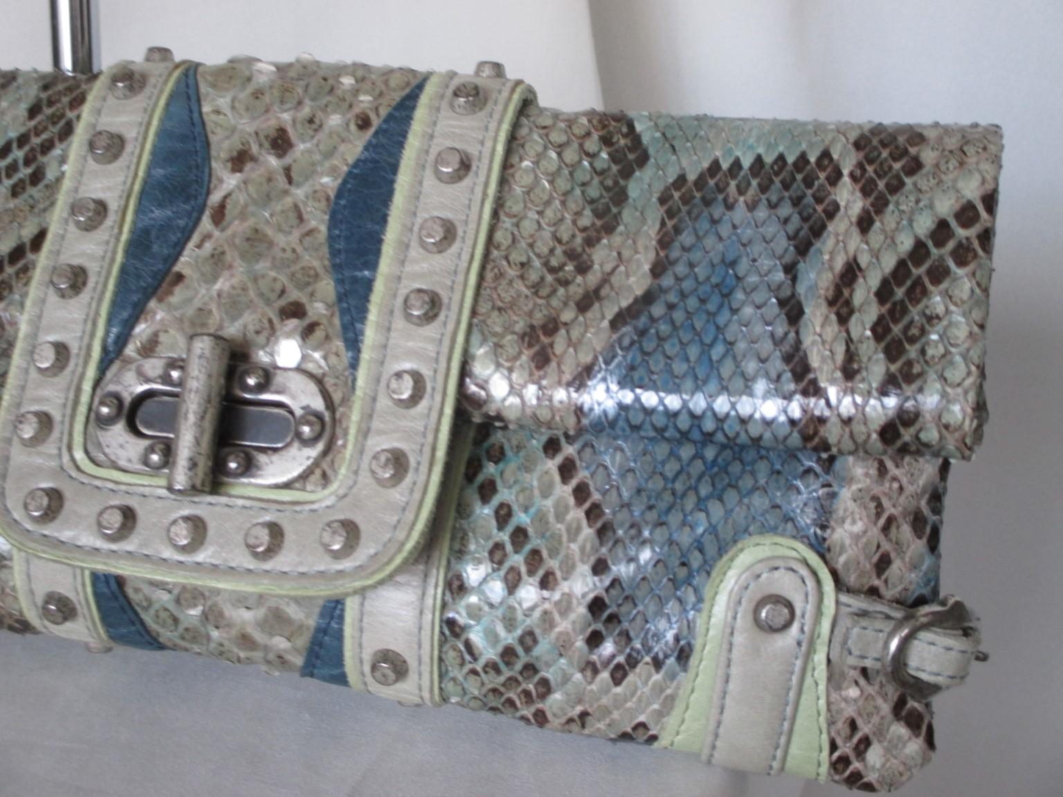 This unique clutch is made from dyed blue/grey/green/silver python leather.

We offer more luxury bags, fashion and furs, view our frontstore.

Details:
Fully lined 
With fringe and handle which are removable
Silver tone hardware/studs
Brand: