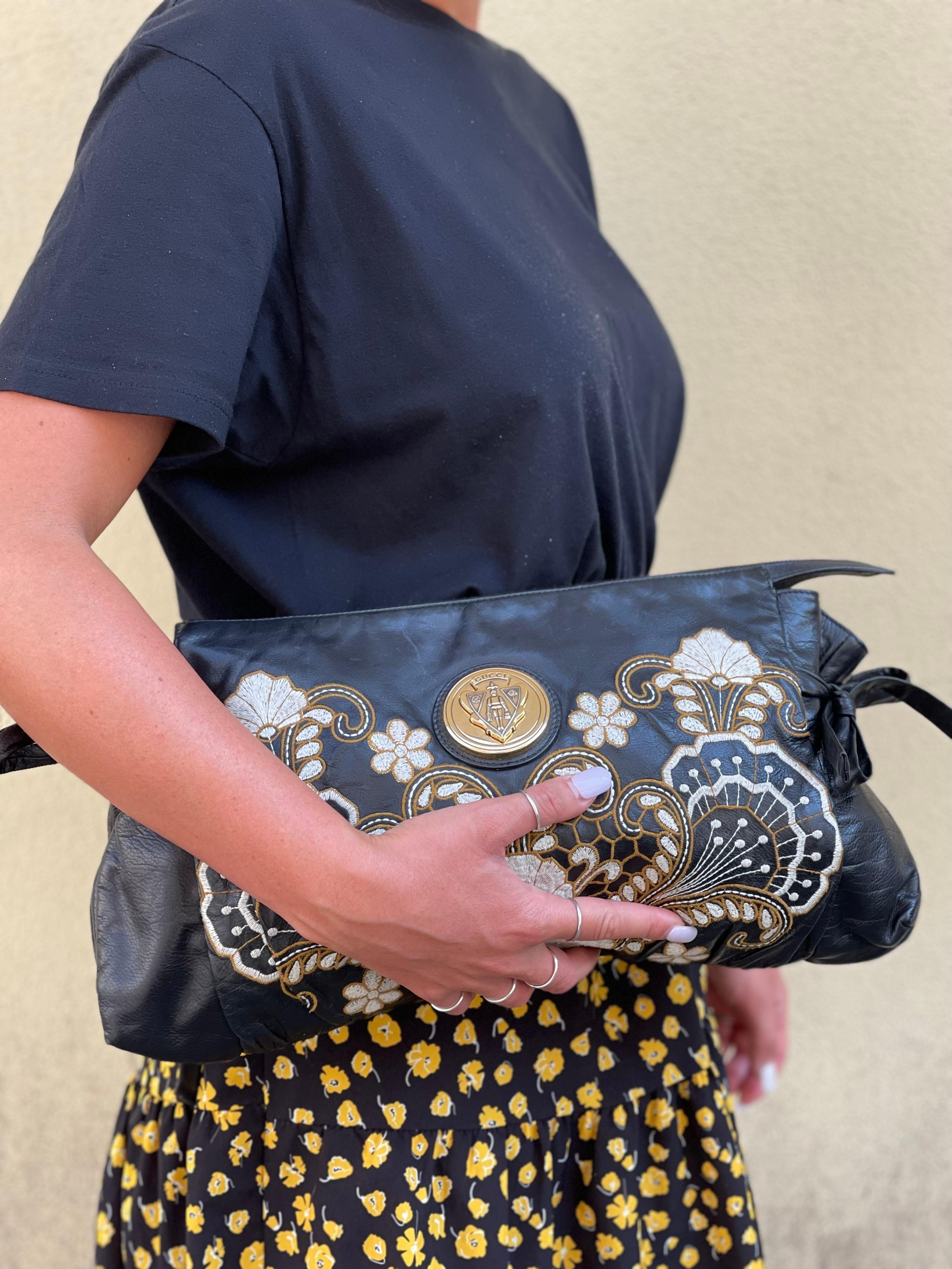Sophisticated Gucci clutch in black leather with floral embroidery. It is characterized by bows on the sides and a large central logo. Excellent condition.
