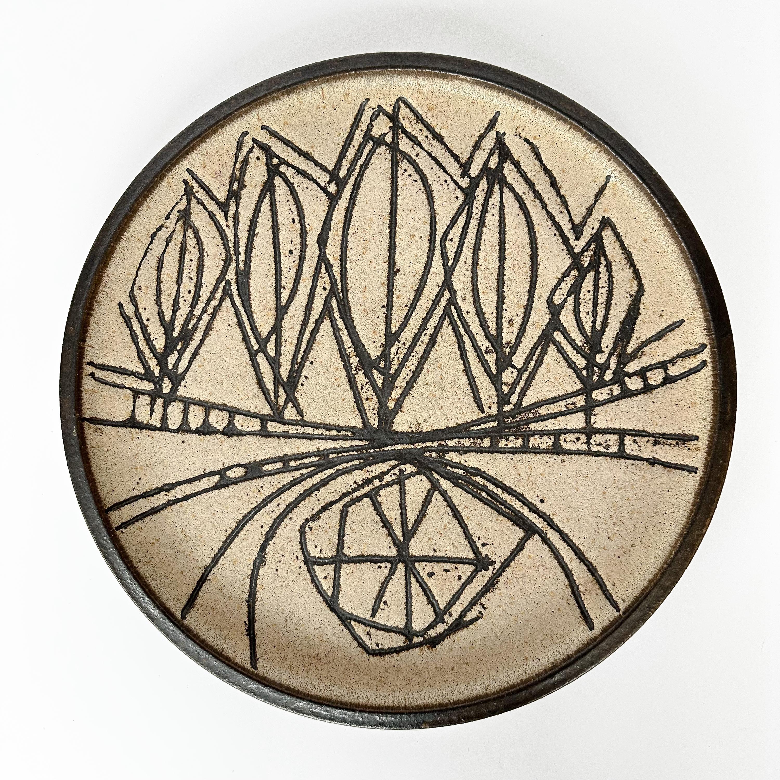 A large Clyde Burt (Ohio, 1922-1981) ceramic charger / plate, circa 1960s. This glazed stoneware charger features a sgraffito abstract design in dark brown on a beige / tan background. Dark brown glazed rim. CB inscribed signature to underside.