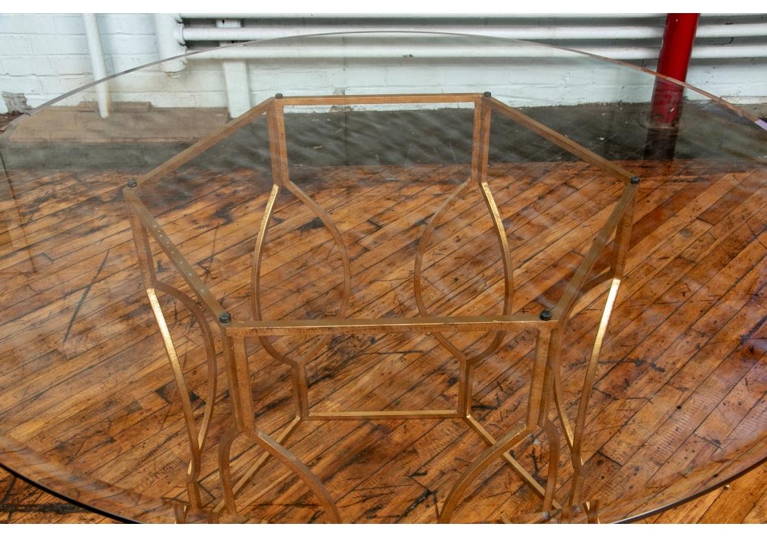 A fine Table for dining or use as a Center Table. The delicate tracery styling of the base is actually tough Gilt Iron. A round table with gilt iron hexagonal base with openwork geometric supports. With a fine beveled rim glass top. 

Diameter  48