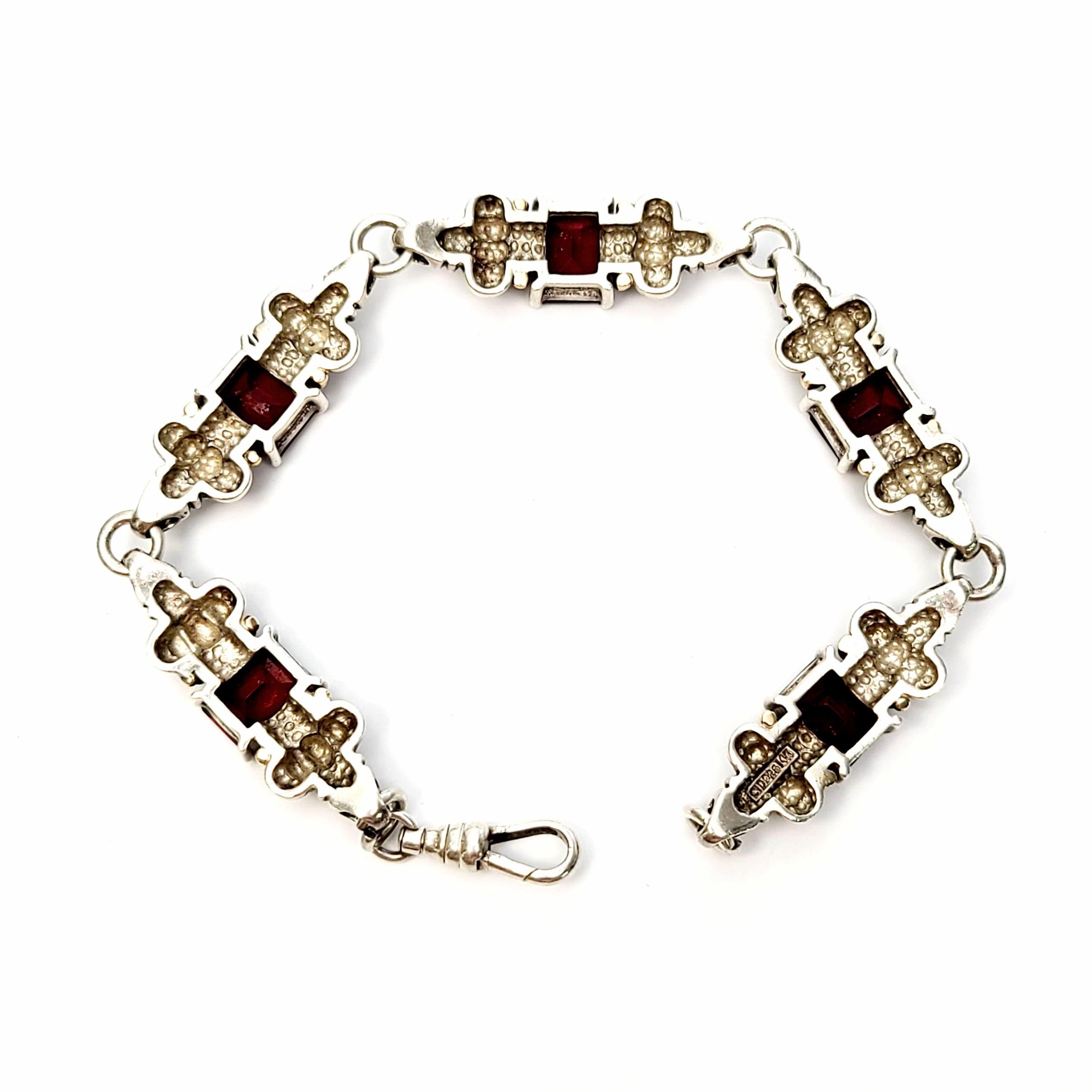 Sterling silver, 14K and garnet bracelet by designer Clyde Duneier.

Beautiful renaissance style piece featuring 5 sterling silver links with an emerald cut, deep red garnet at the center with gold bead accents on either side of each stone. Unique