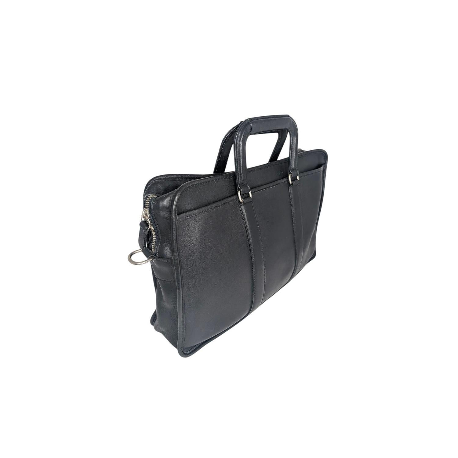 Ce sac messager vintage en cuir Coach est fait de cuir noir luxueux et de ferrures de couleur argentée. Il est doté d'une sangle réglable pour le corps, ce qui en fait un sac à la fois élégant et pratique. La fermeture à glissière s'ouvre sur un