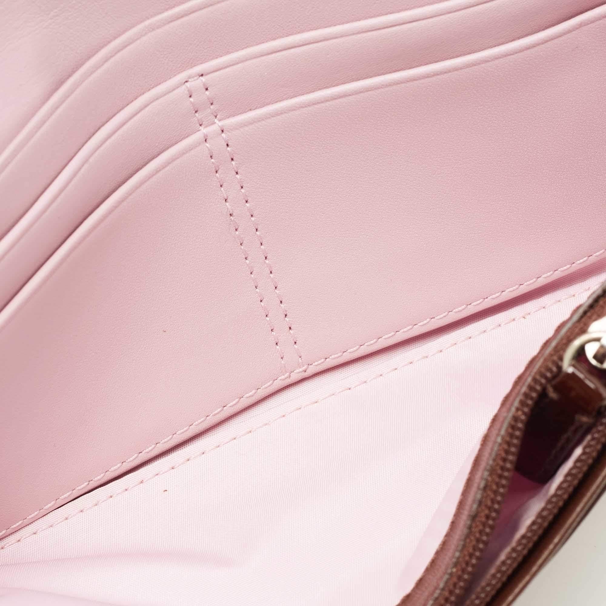 Ce portefeuille Coach est fabriqué en toile et agrémenté de cuir verni. Le portefeuille à rabat s'ouvre sur un intérieur qui abrite plusieurs fentes pour cartes.  deux compartiments ouverts pour les devises et les Billing  et une poche à monnaie