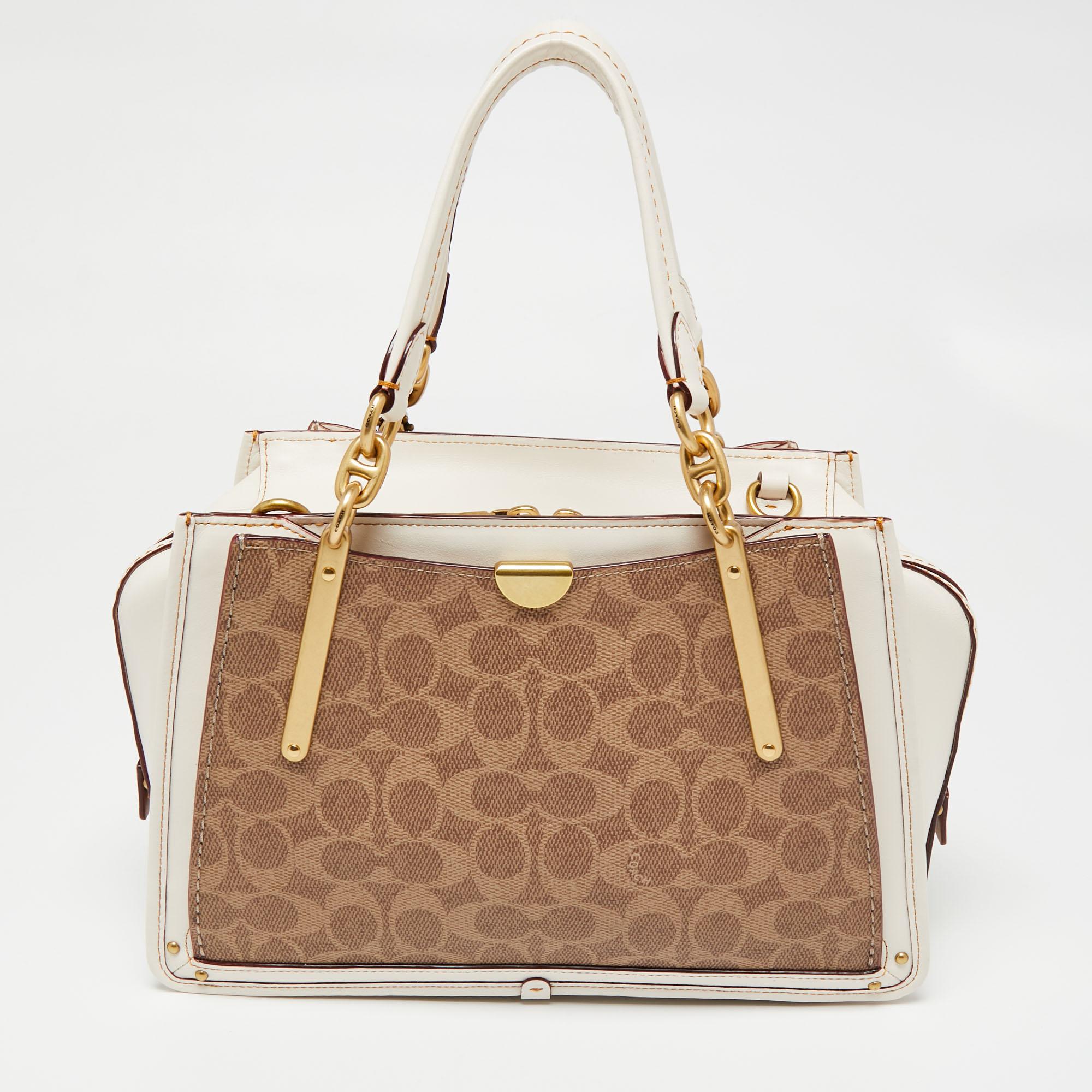 The white trim against the beige exterior lends this Coach Dreamer satchel a luxe contrast. Created from the signature coated canvas and leather, it is defined by dual handles at the top, a shoulder strap, and gold-tone hardware. The top zipper