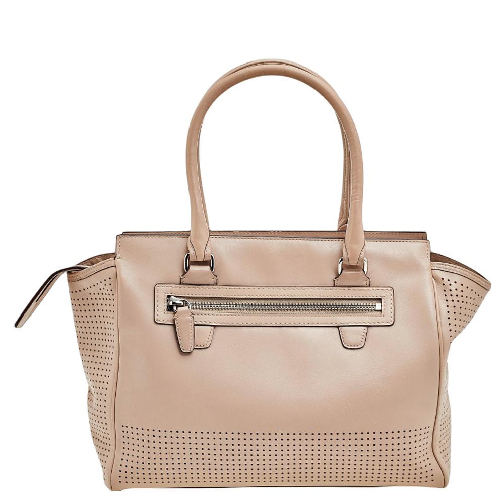 This beautiful Candace Carryall bag from Coach is highly functional and full of charm. Crafted from beige leather, the bag features dual handles, perforated detailing, red tassels, and silver-tone hardware. The fabric-lined interior will hold all