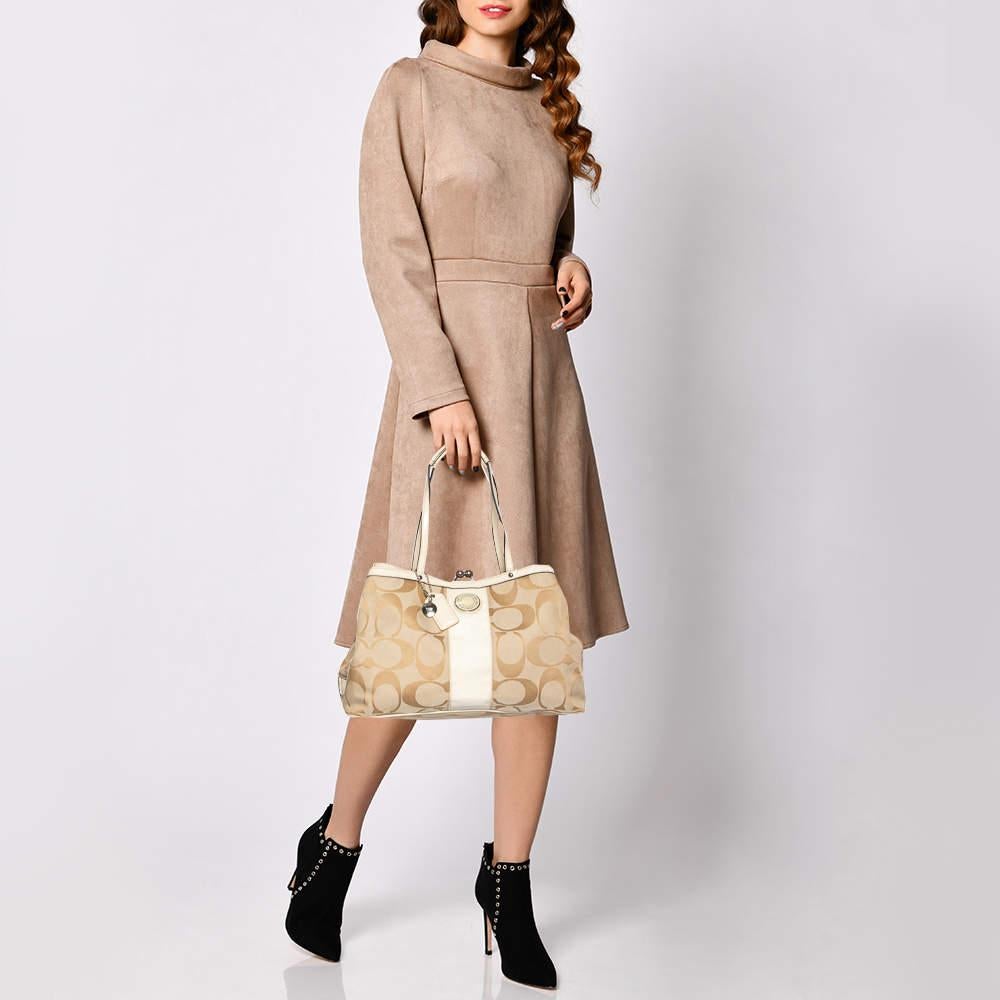 Meticulously crafted from signature canvas and leather, this Coach Carryall tote has a spacious interior divided by a kiss lock compartment. Use the two shoulder handles to parade this beautiful creation.