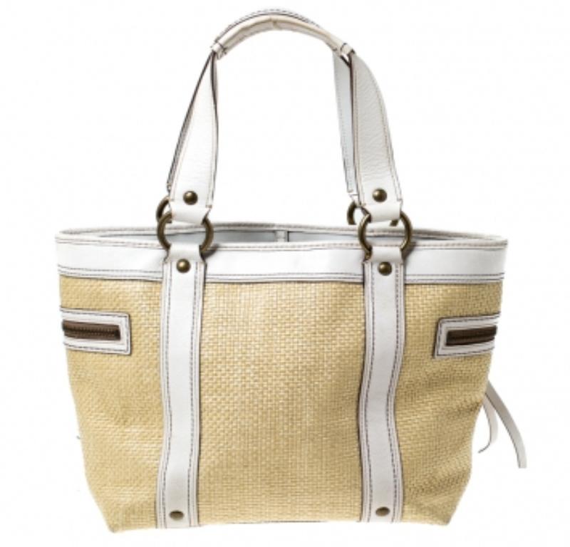 This Coach handbag boasts of style and luxury. Look trendy by adorning this beautiful straw and leather bag that comes with side zip pockets and a front pocket. Lined with fabric, this bag is just about perfect for the essentials and can be carried