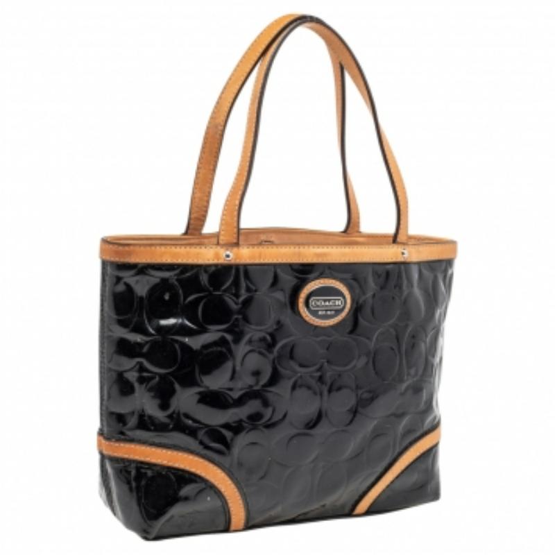 Jede moderne Garderobe braucht eine Coach-Handtasche wie diese. Sie ist aus dem für die Marke charakteristischen, geprägten Lackleder gefertigt und kommt in schönen Schwarztönen mit beigen Lederbesätzen daher. Sie ist mit zwei Griffen, einer