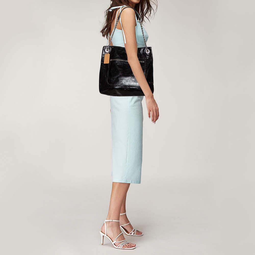 Minimalistic, stylish, and ideal for daily use, Coach's tote is a must-have for a modern woman. Crafted from crackled leather in a black shade, it features a front zip pocket and a capacious satin-lined interior for your belongings. The bag suspends