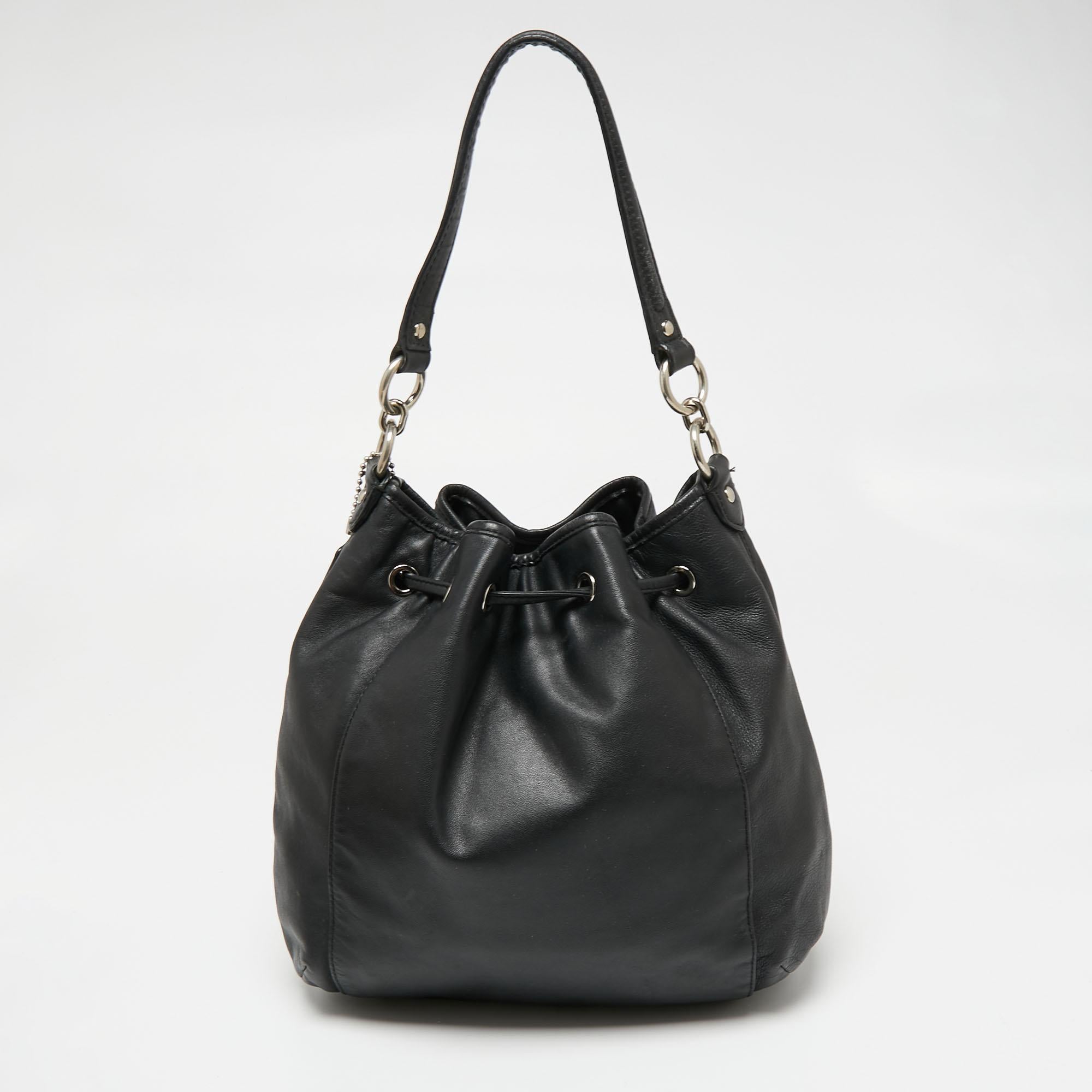 This crossbody bag by Coach is a great option for carrying your essentials. This black leather bag has a compact size and a drawstring to secure the satin interior. Designed to be ideal for everyday use, this crossbody bag is a must-have.

