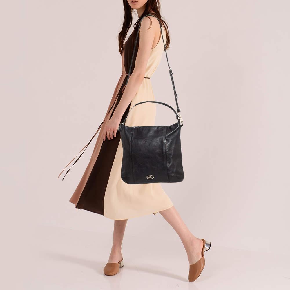This Coach hobo is tailored to exude finesse and functionality while completing your ensemble with style. It features a well-crafted exterior adorned in a lovely hue and a spacious interior. Add some extra style to your everyday looks with this