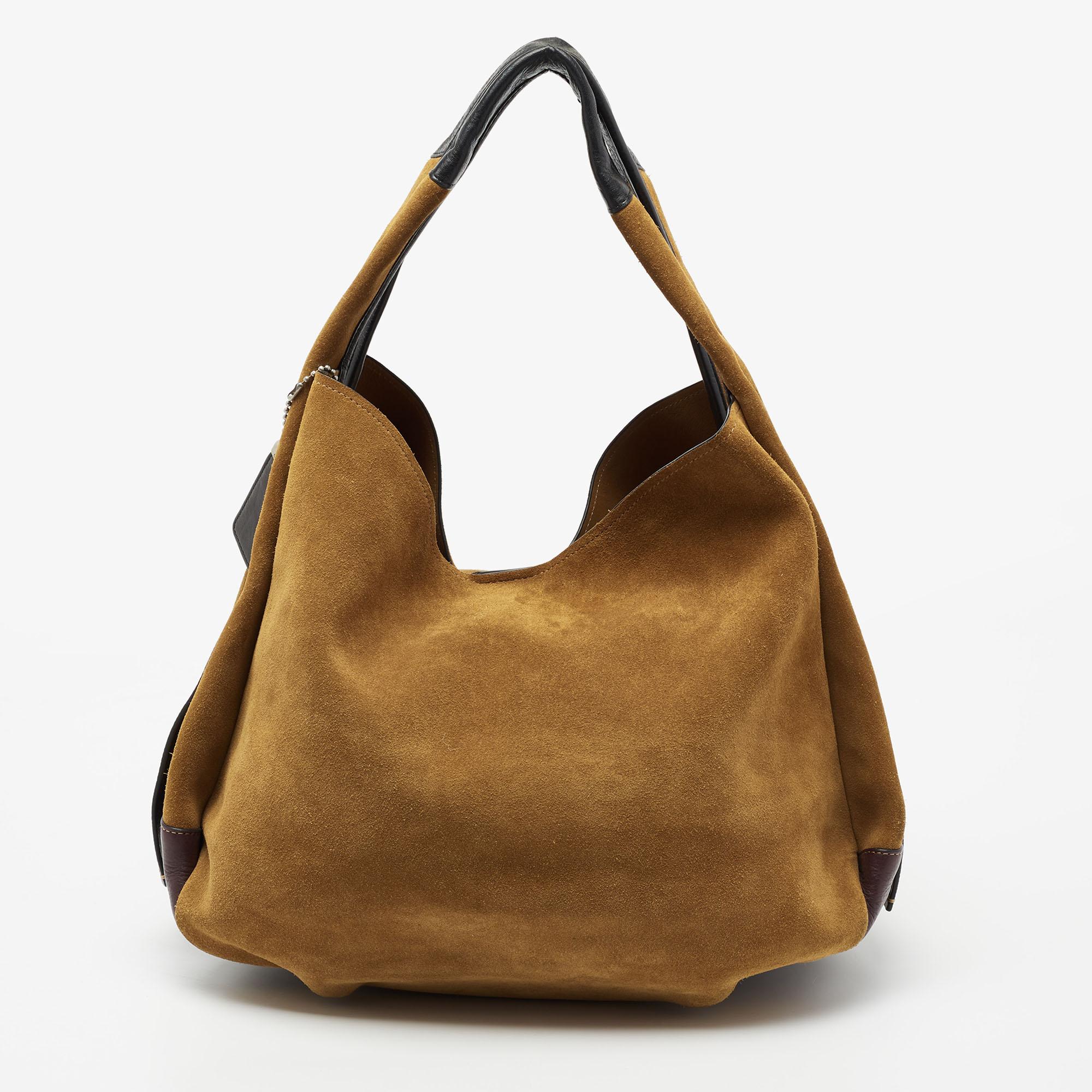 This beautiful Bandit hobo from Coach is highly functional while being charming and stylish. Crafted from brown leather and suede, the bag features dual handles, protective metal feet, and silver-tone hardware. The spacious interior is leather-lined