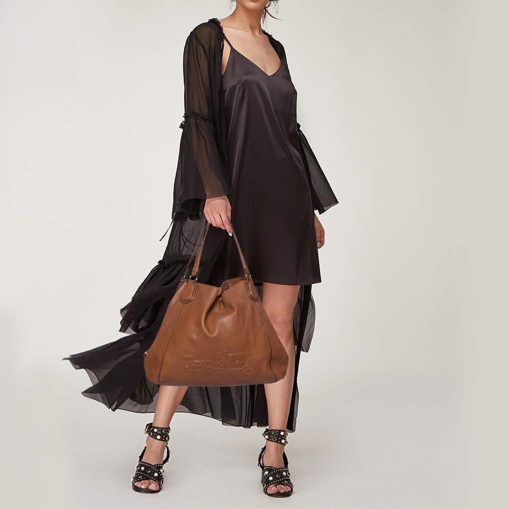 This Edie Carriage shoulder bag by Coach is an ideal option for keeping your daily essentials safe. Lined with fabric, added with gold-tone hardware, and the logo at the front, it is just about perfect to use every day. Comfortable and easy to