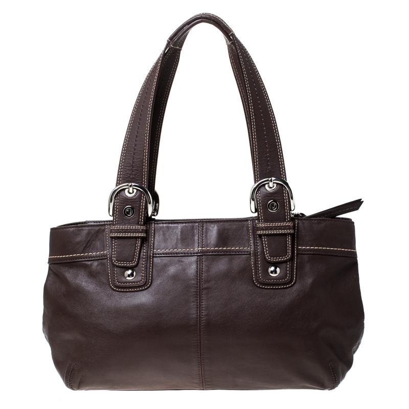 This Coach tote is here to complement all your fashionable outings. Crafted from brown leather, the tote comes with dual handles, protective metal feet, and a Coach tag. The zip top closure opens to a spacious nylon lined interior that houses slip