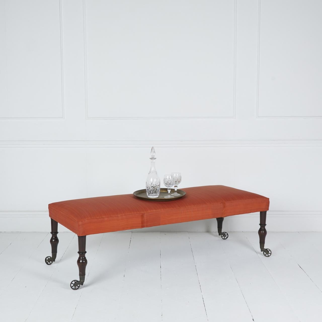 Coach-built stool covered in orange horsehair fabric
standing on English antique turned legs and period spoked castors.

Suitable as a coffee table, bed end or window seat.

Mainland delivery FOC International POA US 14 day

Dimensions: H 17″  W 22″
