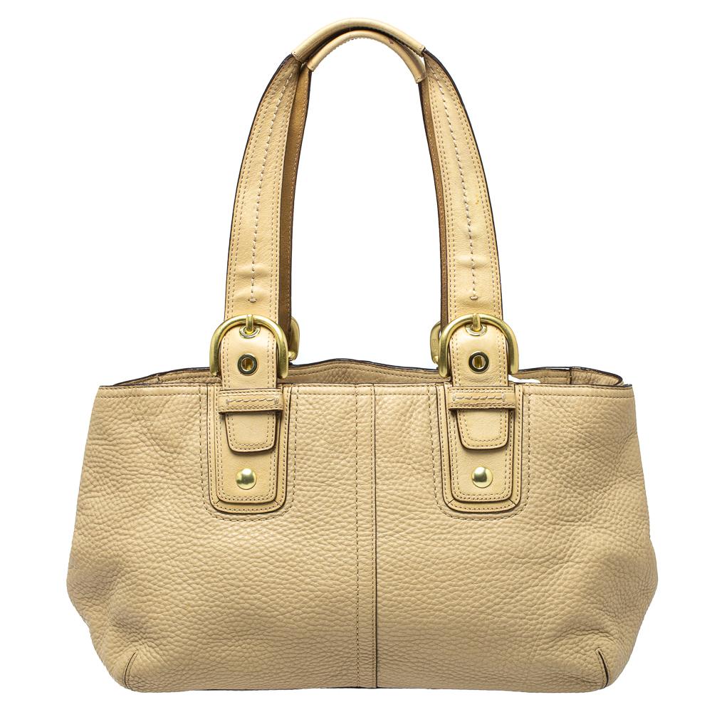 Masterfully created, this Soho tote by Coach is a style icon you cannot do without. Crafted from leather in a cream shade, the bag is equipped with a spacious interior for your daily essentials. It suspends from dual handles adorned with gold-tone