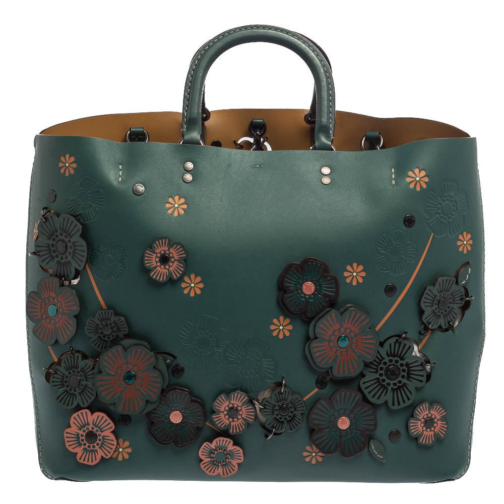Vividly detailed and finely crafted from leather, this Rogue tote from Coach is delightful! It features beautiful floral appliques on the front and the back and comes equipped with dual handles. It opens to a capacious fabric interior that can