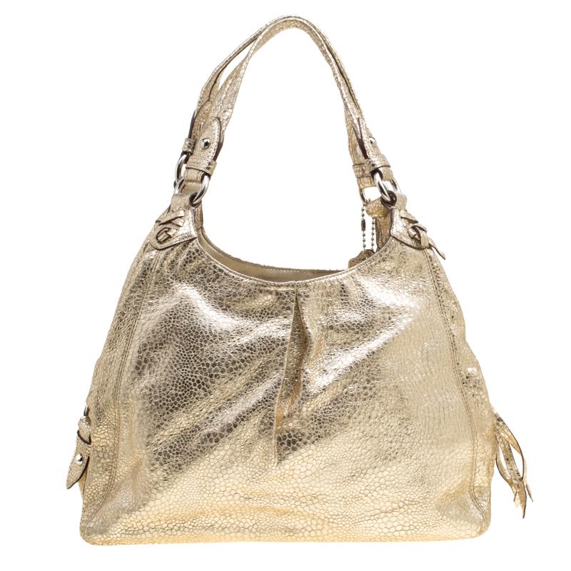 This Coach tote is here to complement all your fashionable outings. Crafted from gold embossed leather, the tote comes with dual handles, protective metal feet, and a Coach tag. The zip top closure opens to a spacious satin lined interior that