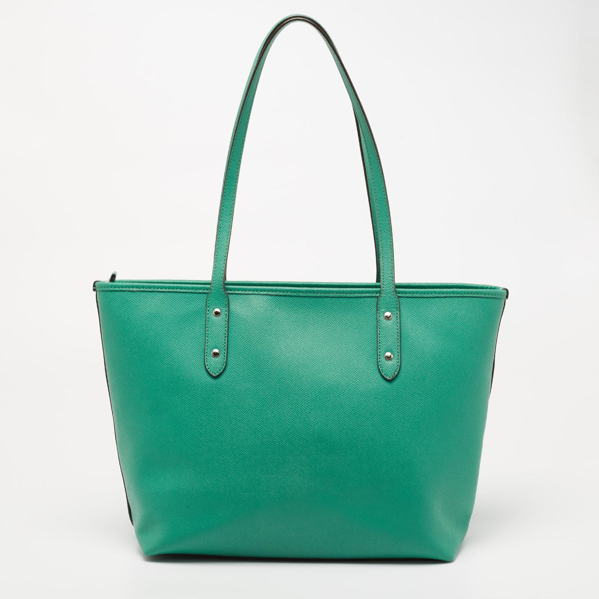 This City Zip tote from the House of Coach is great for everyday use. It is made from green leather, which is embellished with silver-tone hardware. It showcases dual handles and a fabric-lined interior. This tote will make you look classy and