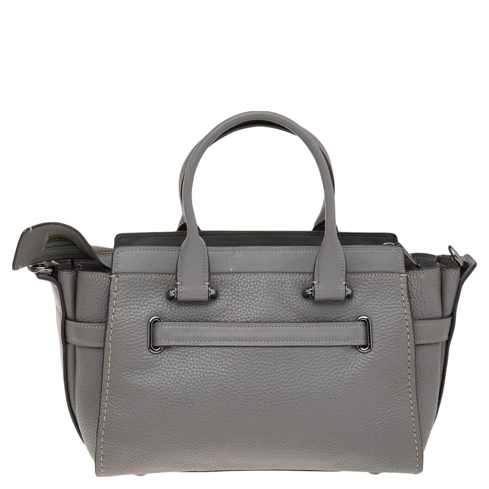 This beautiful Carryall satchel from Coach is highly functional while being charming and stylish. Crafted from grey leather, the Swagger 27 Carryall bag features dual handles and gunmetal-tone hardware. The lined interior will hold all your