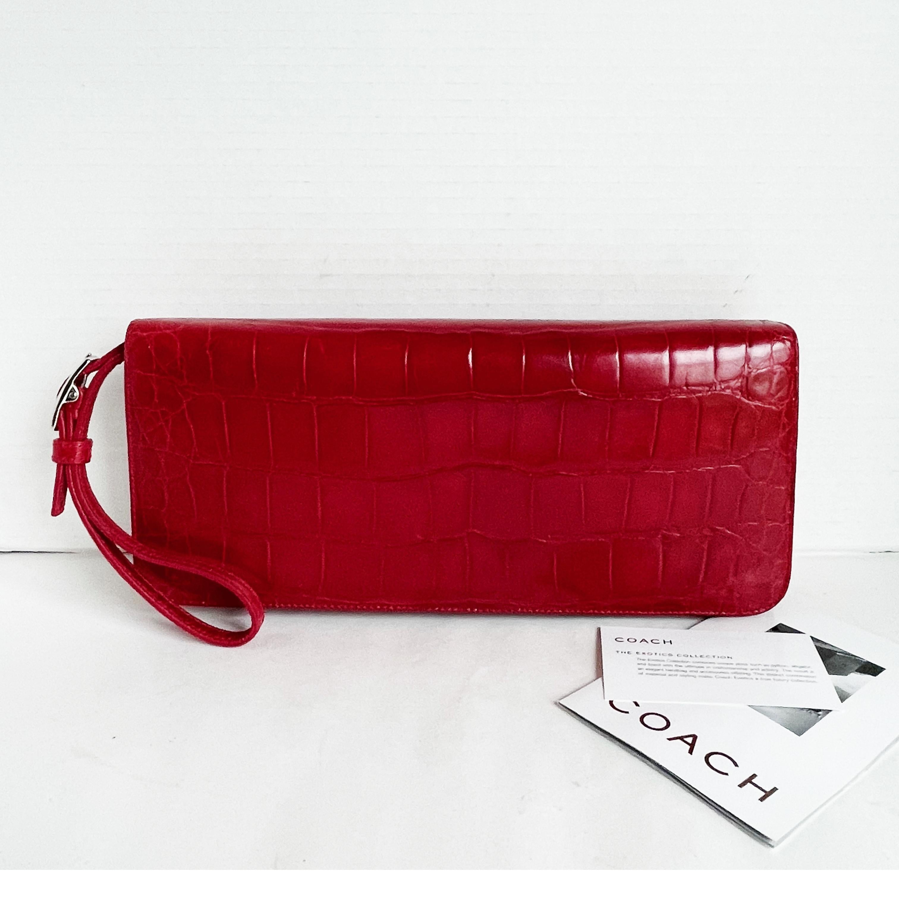 Authentic, preowned Limited Edition Coach Alligator clutch or wristlet bag, from the 2001 Exotic Collection. 

Made from a brilliant glossy red genuine alligator skin, it features a small card slip pocket under the flap and is lined in vachetta &