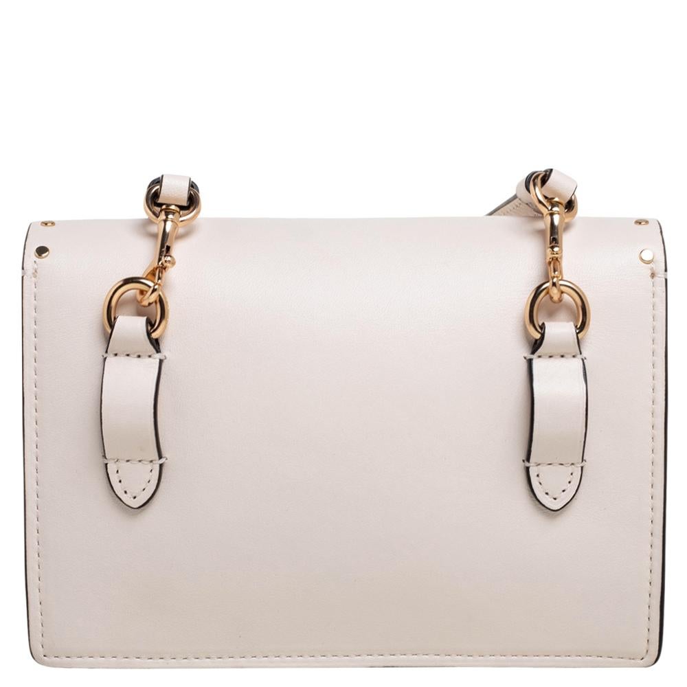 Ce sac à bandoulière Rivets Klare de la maison Coach est super élégant et tendance ! Il est confectionné en cuir beige clair et en toile enduite à l'extérieur et est doté d'une quincaillerie dorée, d'un intérieur doublé en Alcantara et d'une