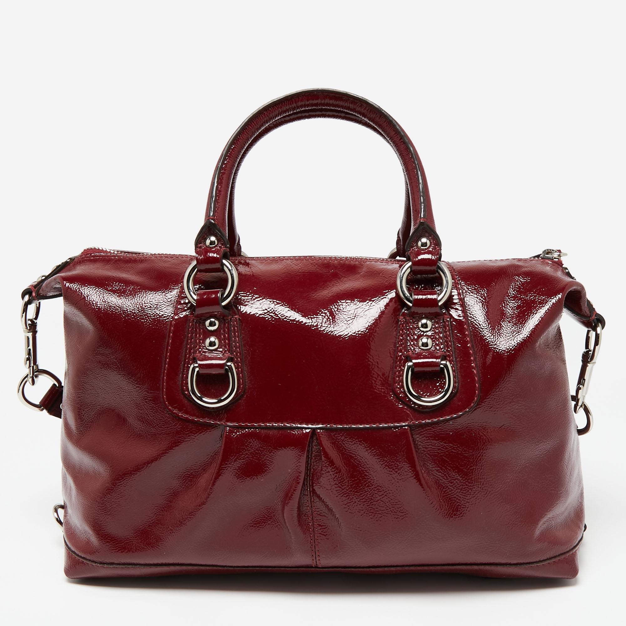 This Coach Ashley tote is an ideal accessory for various occasions. Made from patent leather, it has pleat detailing, silver-tone accents, and a brand detailing on the front. The multiple handling options and a spacious satin-lined interior make