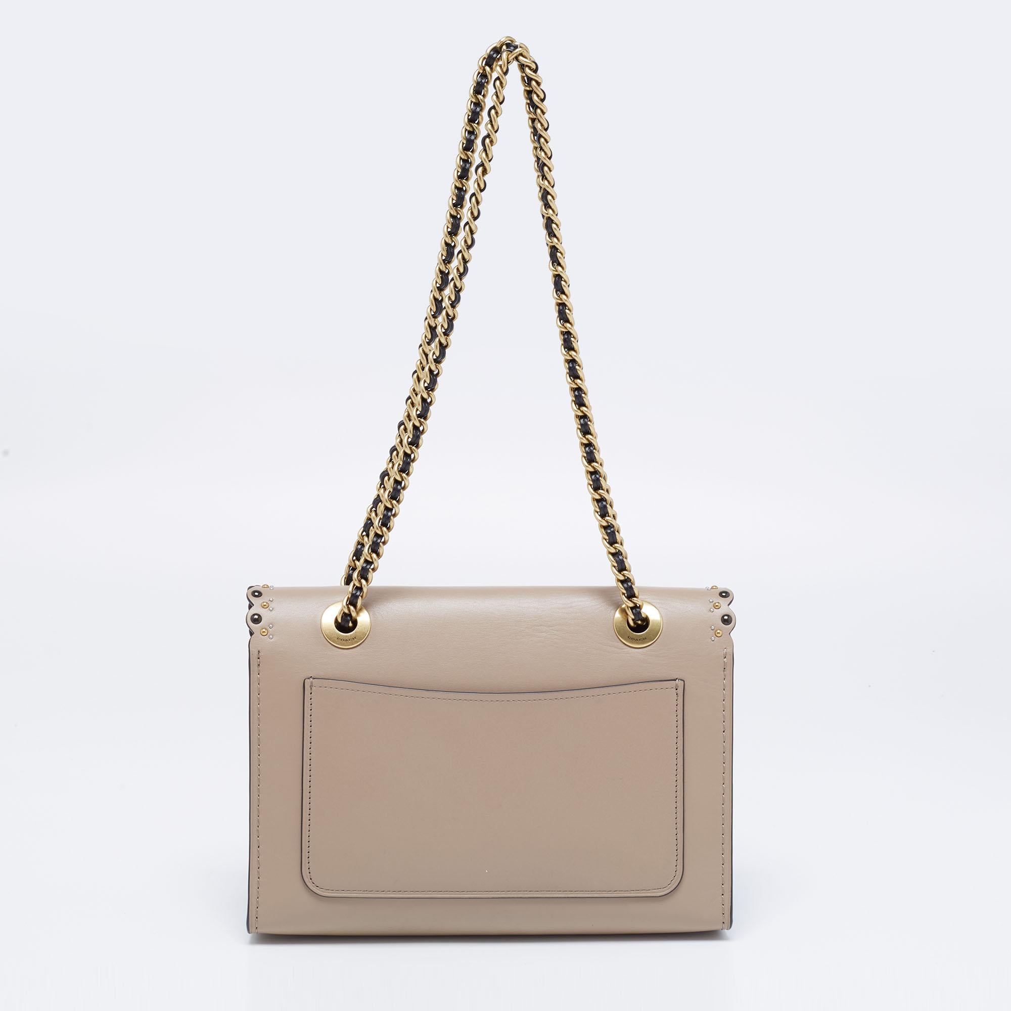 A classic design with a modern touch, this Coach shoulder bag is a beautiful accessory to compliment your outfits. Crafted from scalloped, studded leather, the bag is enhanced with gold-tone hardware and double chain handles. The cute turnlock