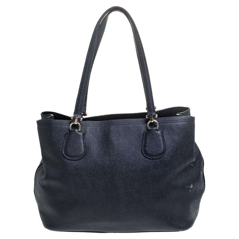 This beautiful Carryall bag from Coach is highly functional while being charming and stylish. Crafted from leather, the bag features dual handles, a brand tag, and gold-tone hardware. The fabric-lined interior comes with two zipped