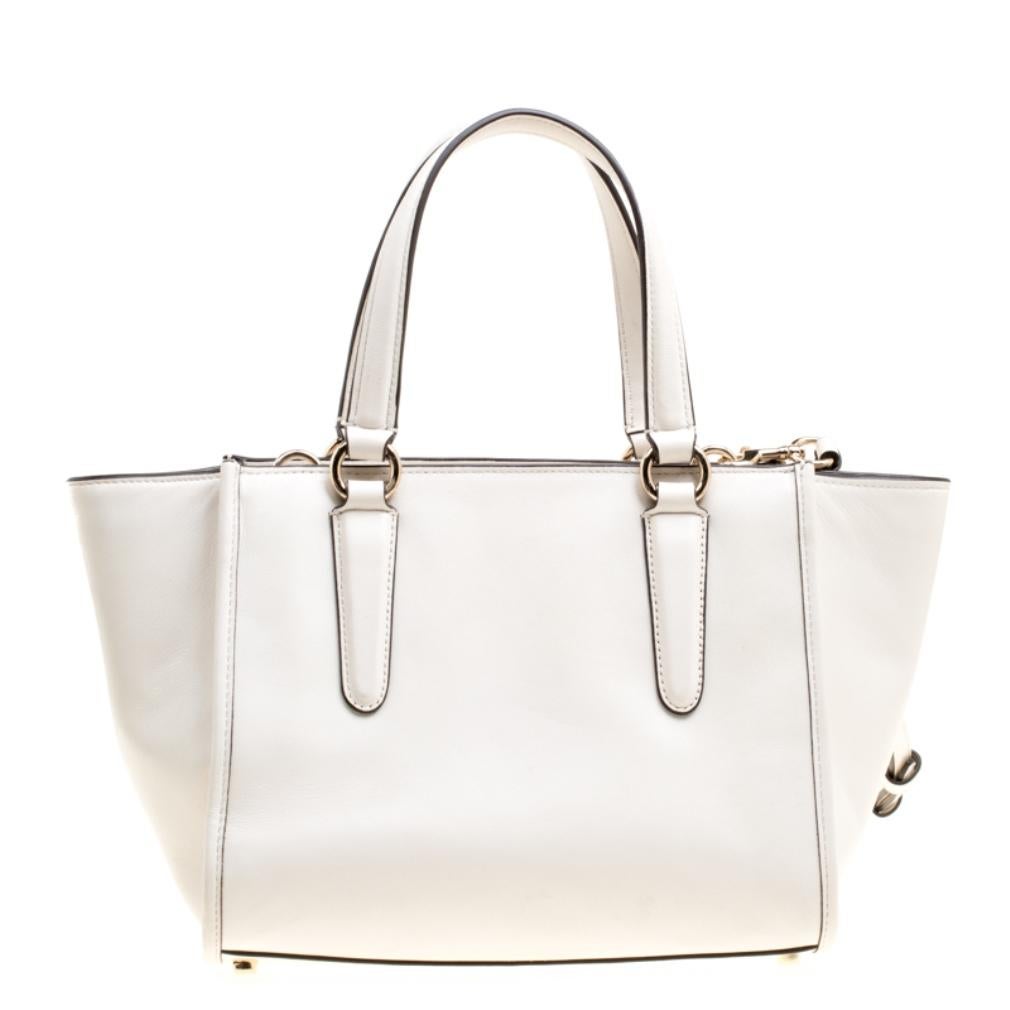 Coach brings you this handy bag that will dutifully support you wherever you go. It has been crafted from leather in off-white, detailed with flowers and eyelets, and equipped with a zipper that secures a spacious fabric interior capable of holding