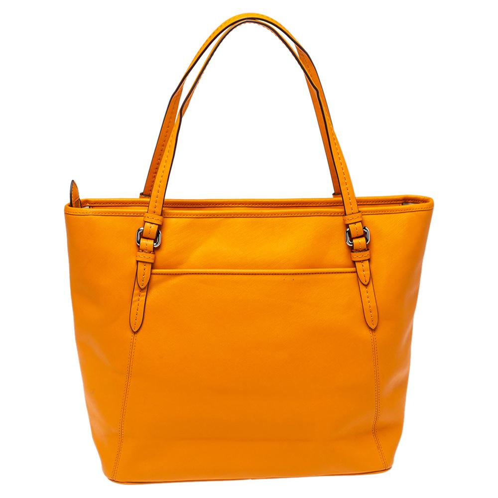 Coach presents a meticulously crafted elegant tote for the fashionable you. This stylish leather handbag comes in a vibrant orange hue. It is held by dual handles and has a fabric interior. The bag is finished with the brand logo on the front and